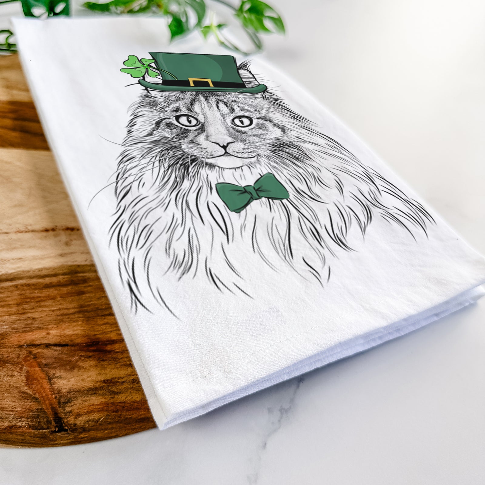 Hand-drawn sketch of Kiki the Maine Coon Cat wearing a St. Patrick's Day leprechaun hat and bow tie on a tea towel