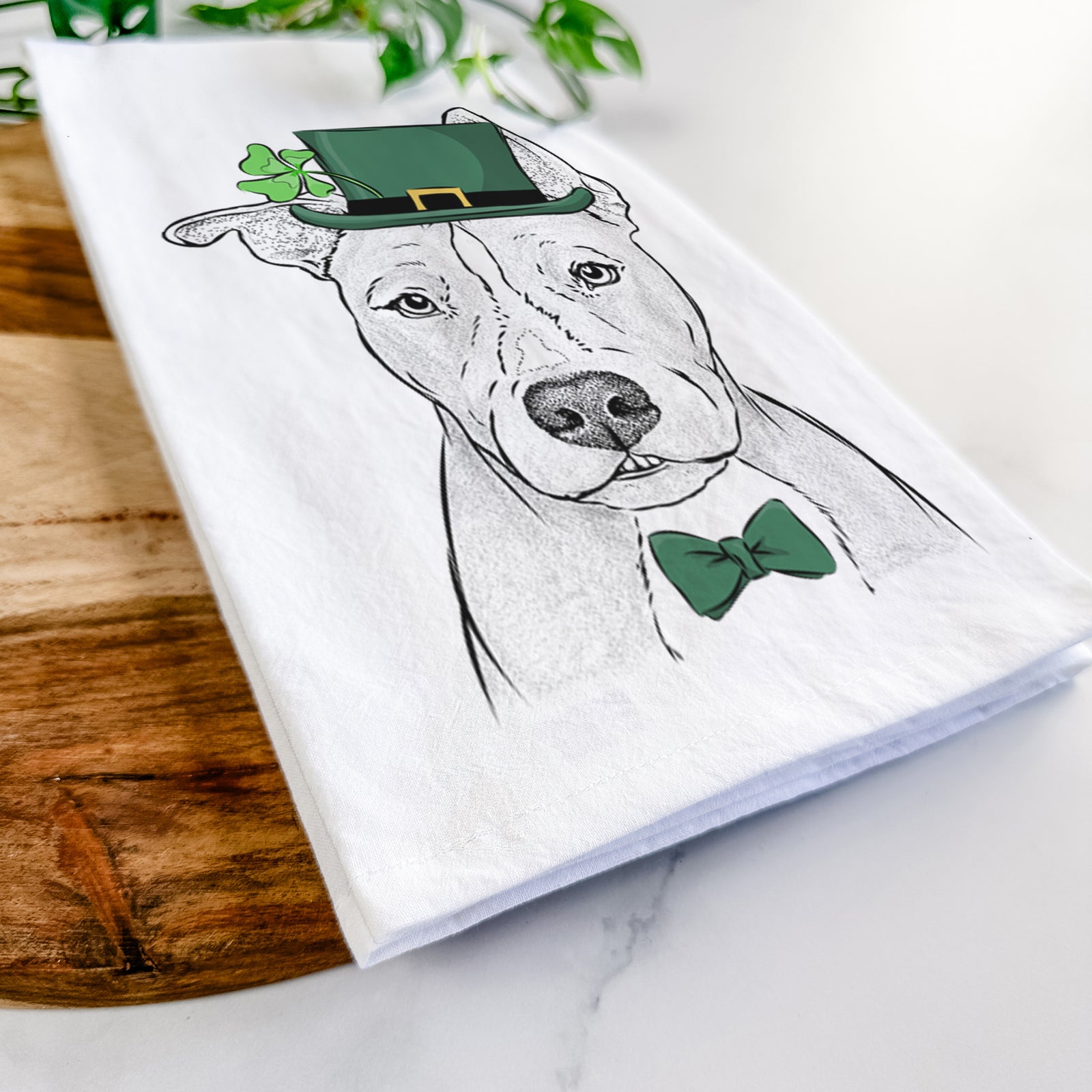 Hand-drawn sketch of Kisses the Pitbull wearing a St. Patrick's Day leprechaun hat and bow tie on a tea towel
