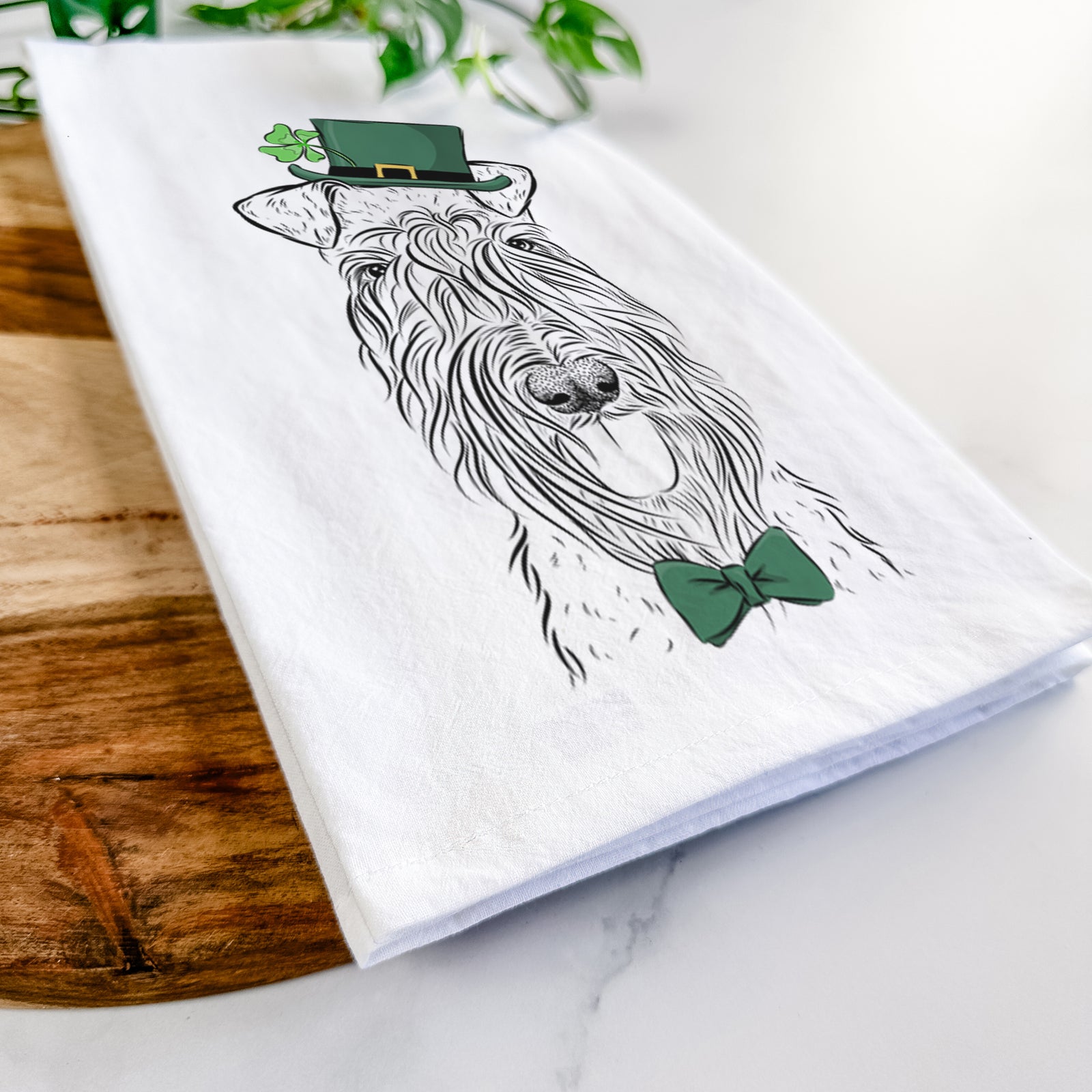 Hand-drawn sketch of Kricket the Kerry Blue Terrier wearing a St. Patrick's Day leprechaun hat and bow tie on a tea towel