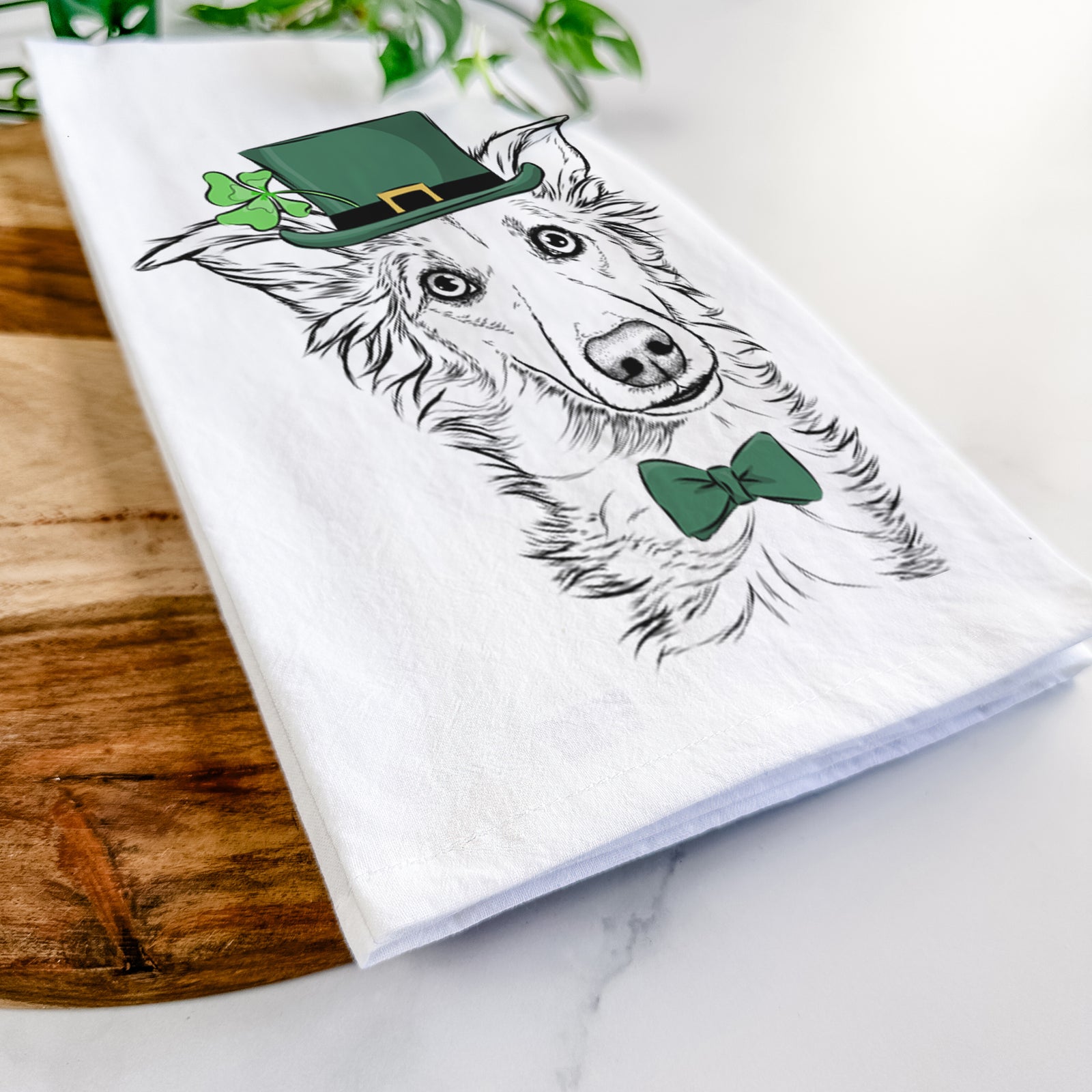 Hand-drawn sketch of Kyu the Windsprite wearing a St. Patrick's Day leprechaun hat and bow tie on a tea towel