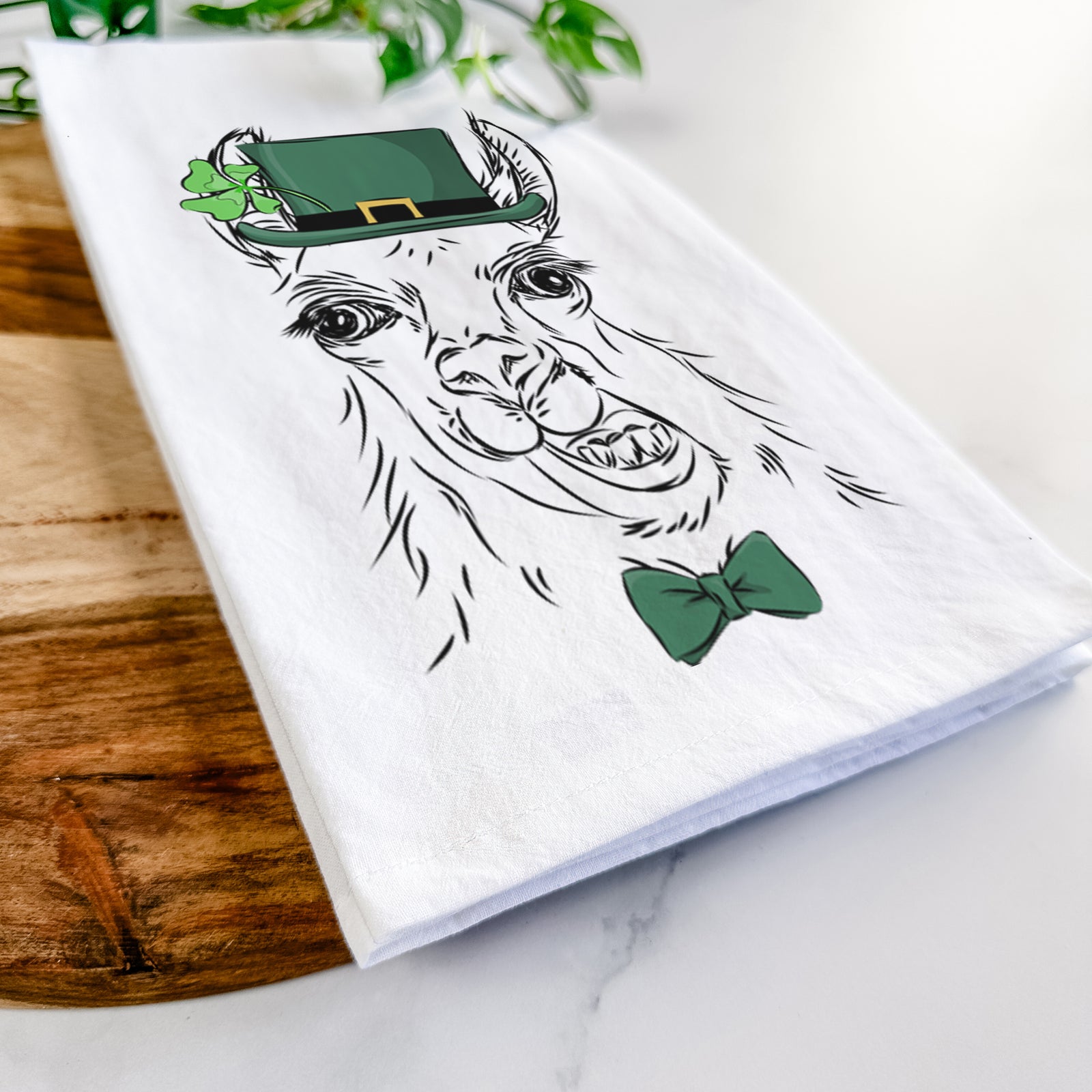 Hand-drawn sketch of Larry the Llama wearing a St. Patrick's Day leprechaun hat and bow tie on a tea towel