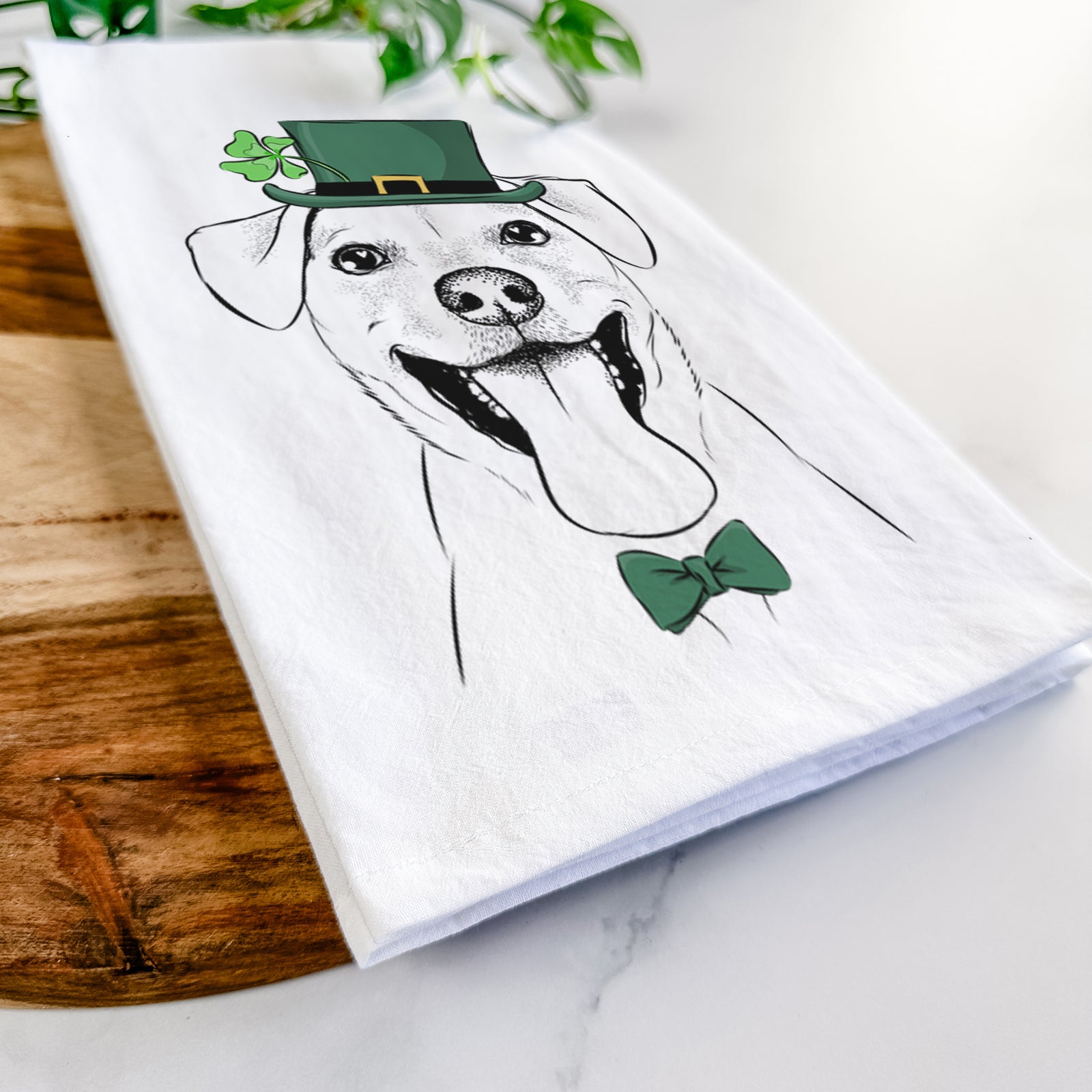 Hand-drawn sketch of Lily Estelle the Mixed Breed wearing a St. Patrick's Day leprechaun hat and bow tie on a tea towel