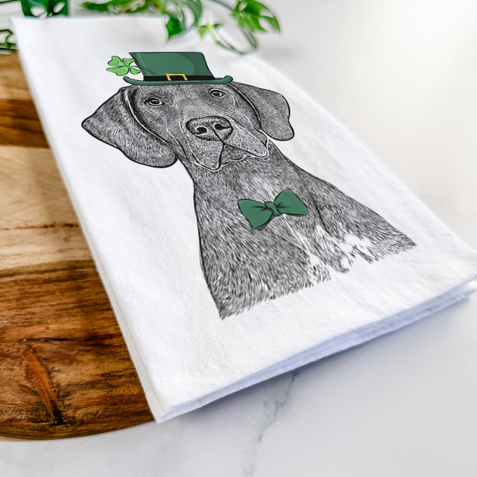 Hand-drawn sketch of Lucifer the German Shorthaired Pointer wearing a St. Patrick's Day leprechaun hat and bow tie on a tea towel
