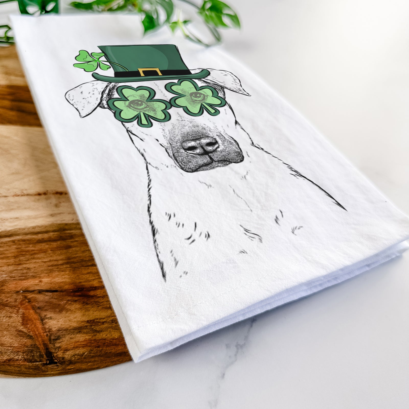 Hand-drawn sketch of Luna the Black Mouth Cur wearing a St. Patrick's Day leprechaun hat and bow tie on a tea towel