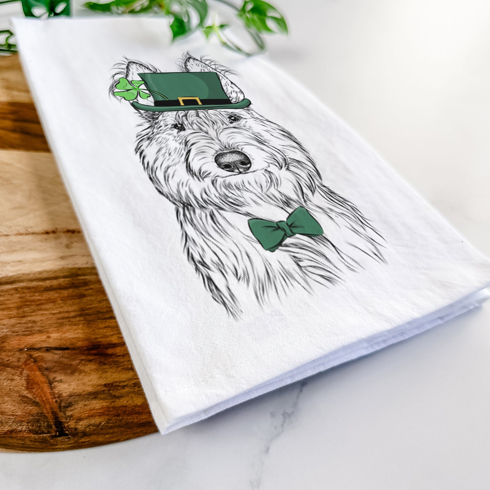 Hand-drawn sketch of Luna the Berger Picard wearing a St. Patrick's Day leprechaun hat and bow tie on a tea towel