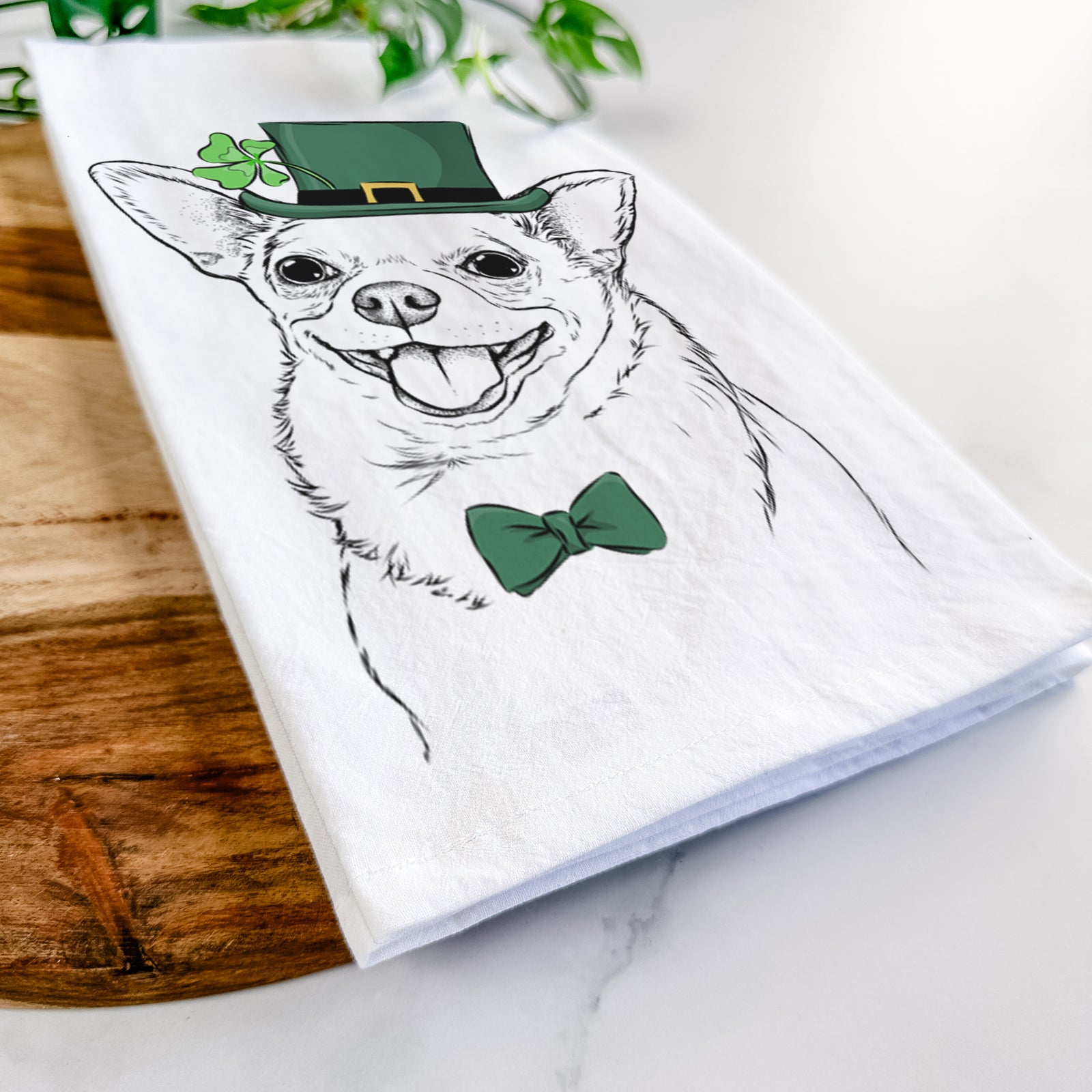 Hand-drawn sketch of Maddison Pearl the Chihuahua wearing a St. Patrick's Day leprechaun hat and bow tie on a tea towel