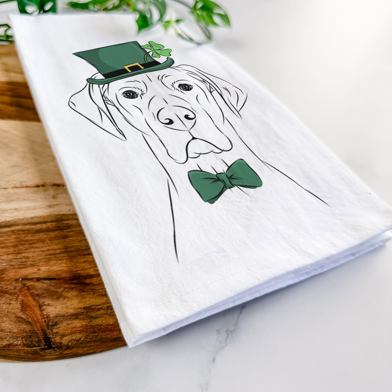 Hand-drawn sketch of Maddox the Great Dane wearing a St. Patrick's Day leprechaun hat and bow tie on a tea towel
