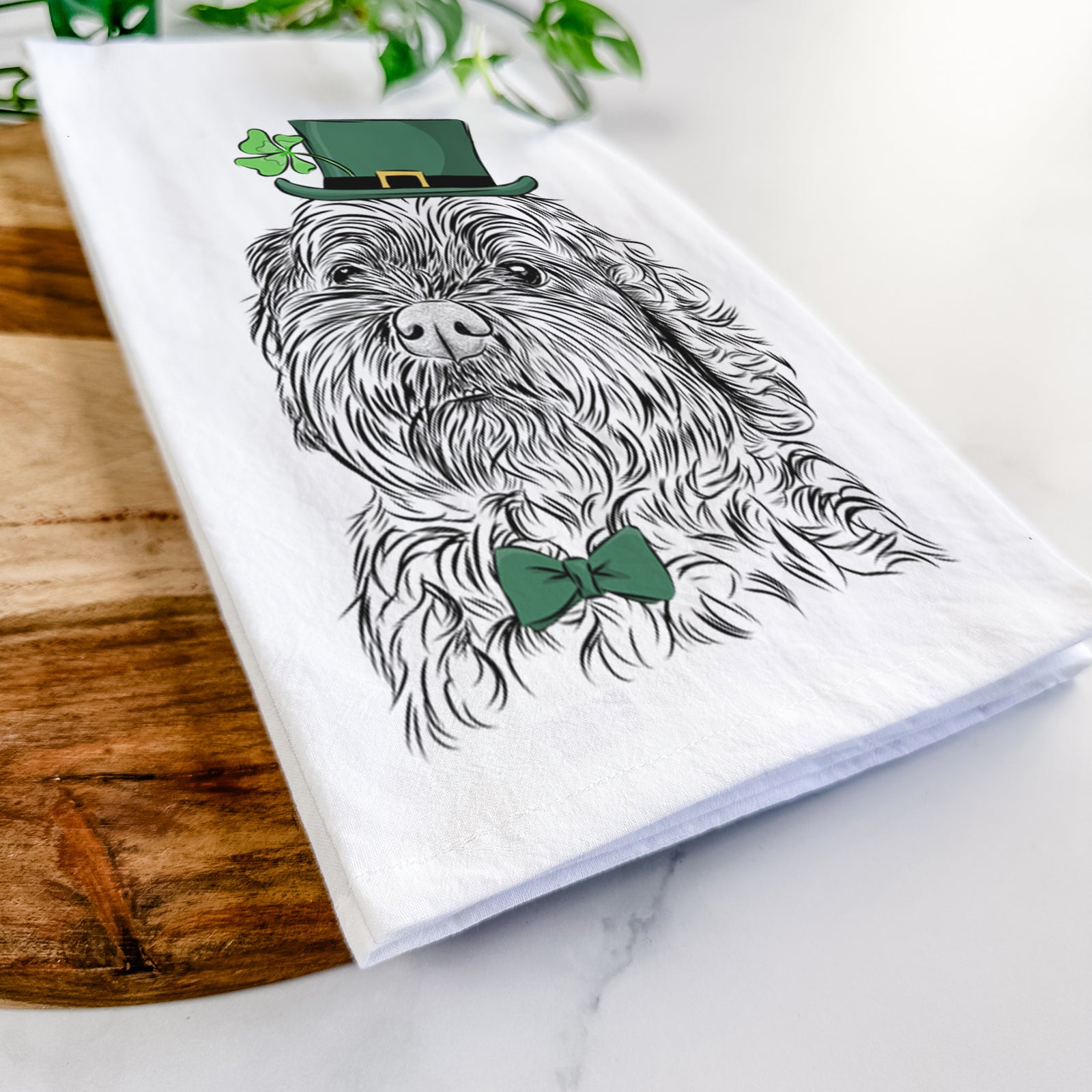 Hand-drawn sketch of Maggie Girl the Cockapoo wearing a St. Patrick's Day leprechaun hat and bow tie on a tea towel