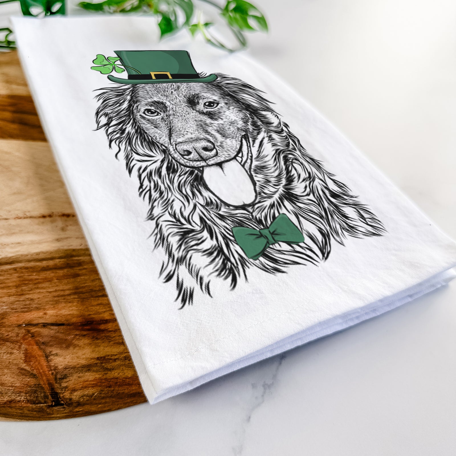 Hand-drawn sketch of Maisie Mae the Aussiedor wearing a St. Patrick's Day leprechaun hat and bow tie on a tea towel