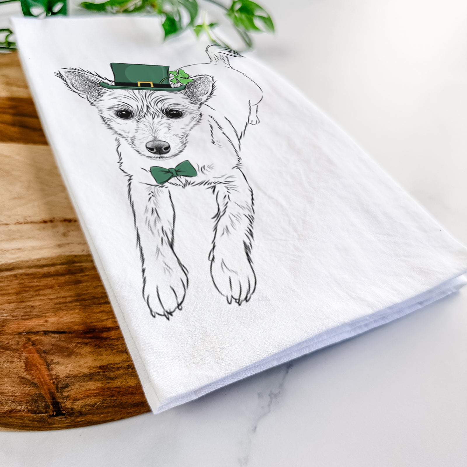 Hand-drawn sketch of Maisie the Terrier Mix wearing a St. Patrick's Day leprechaun hat and bow tie on a tea towel