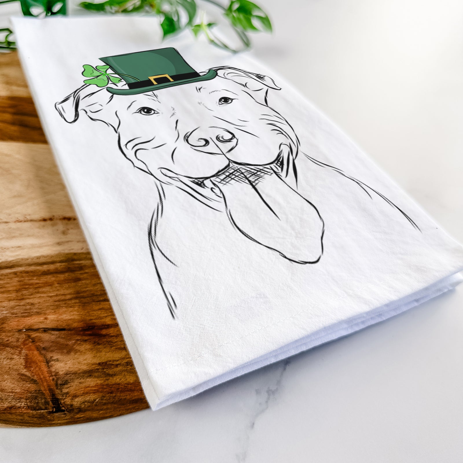 Hand-drawn sketch of Major the Pitbull wearing a St. Patrick's Day leprechaun hat and bow tie on a tea towel