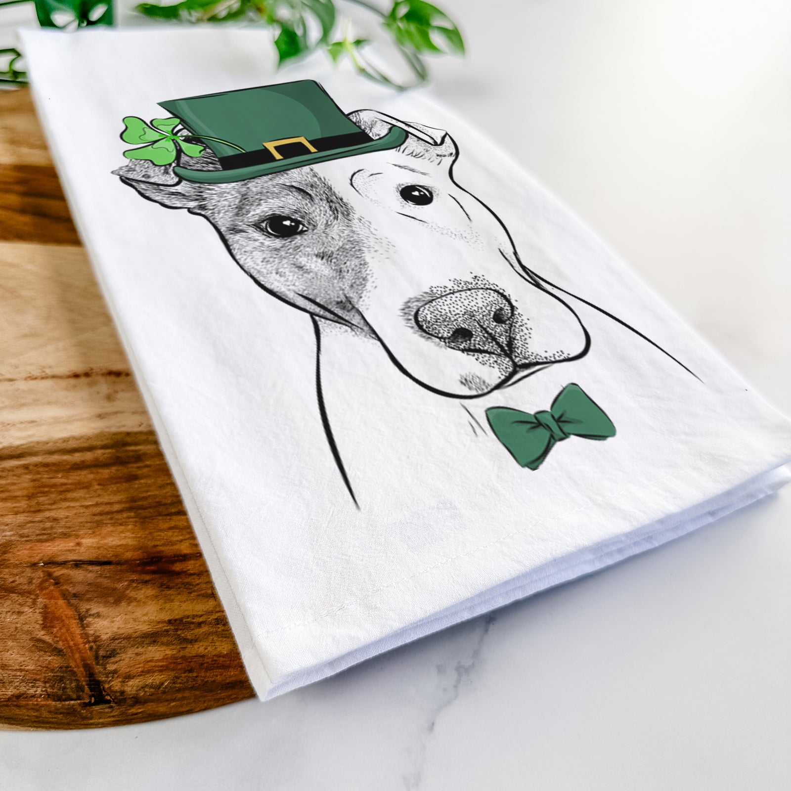 Hand-drawn sketch of Manchi the Pitbull Mix wearing a St. Patrick's Day leprechaun hat and bow tie on a tea towel