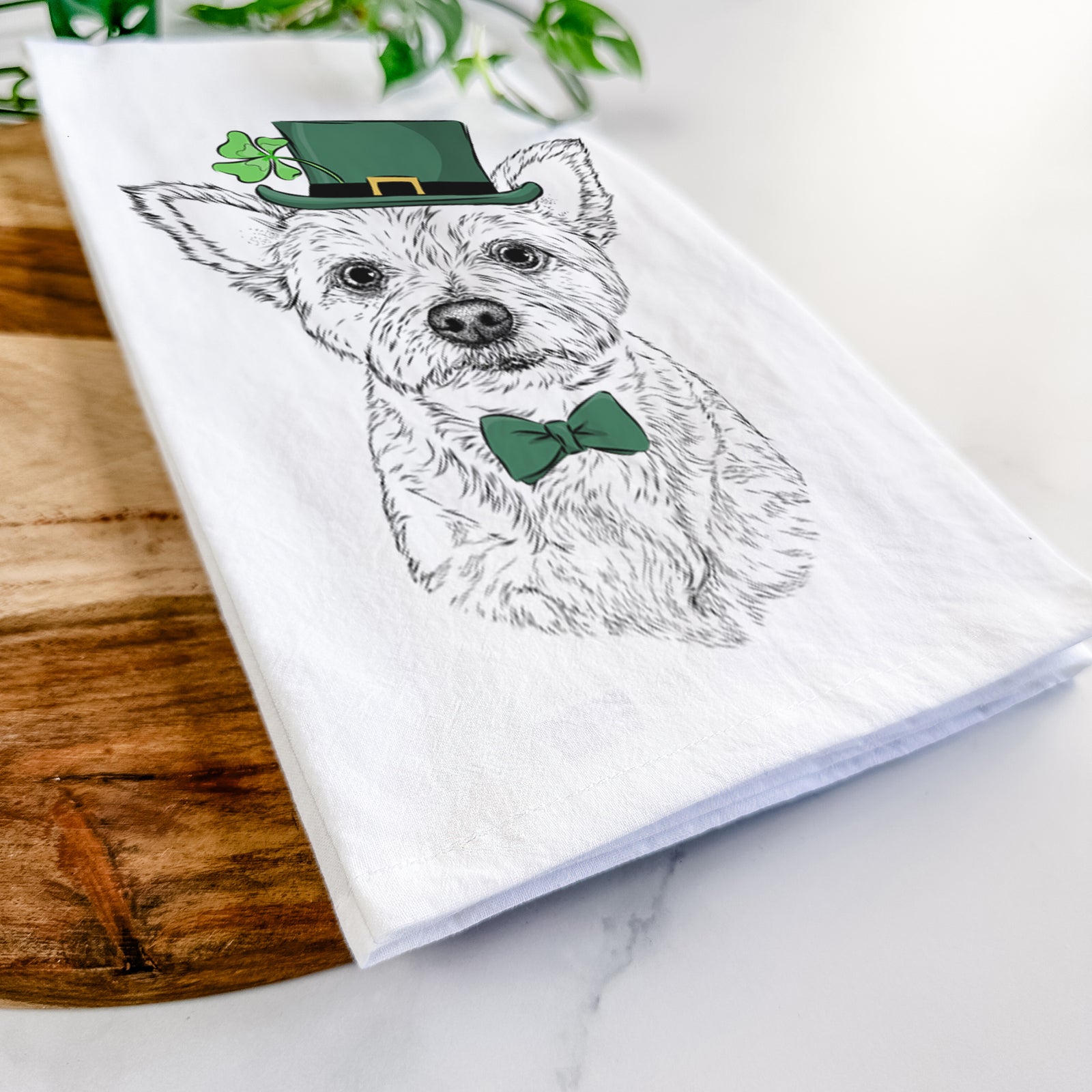 Hand-drawn sketch of Mango the Yorker Cairn Terrier Mix wearing a St. Patrick's Day leprechaun hat and bow tie on a tea towel
