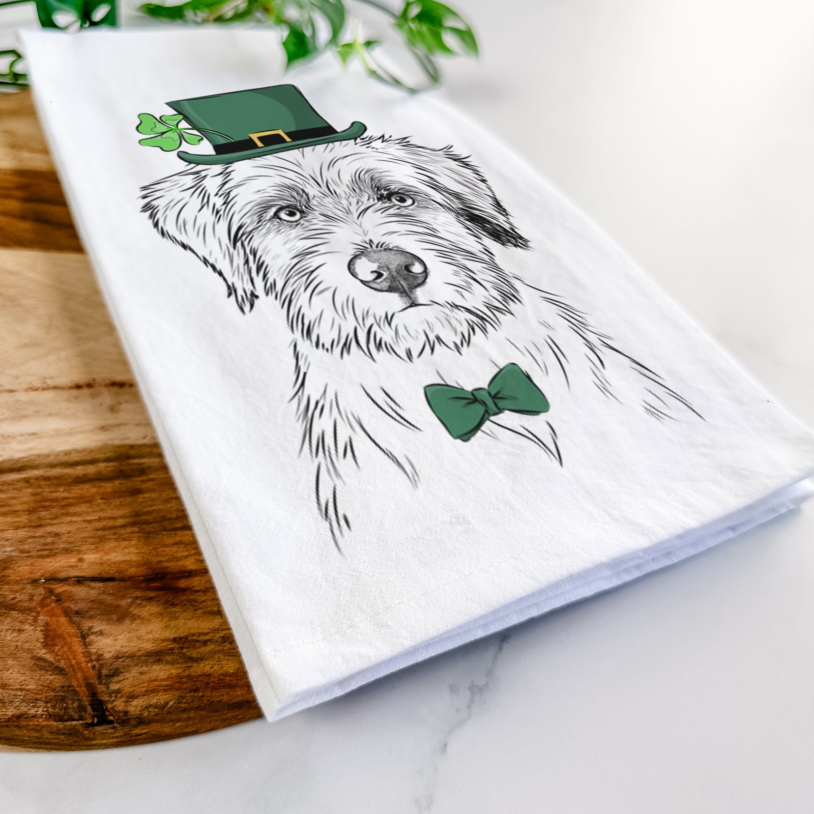 Hand-drawn sketch of Marek the Bernedoodle wearing a St. Patrick's Day leprechaun hat and bow tie on a tea towel