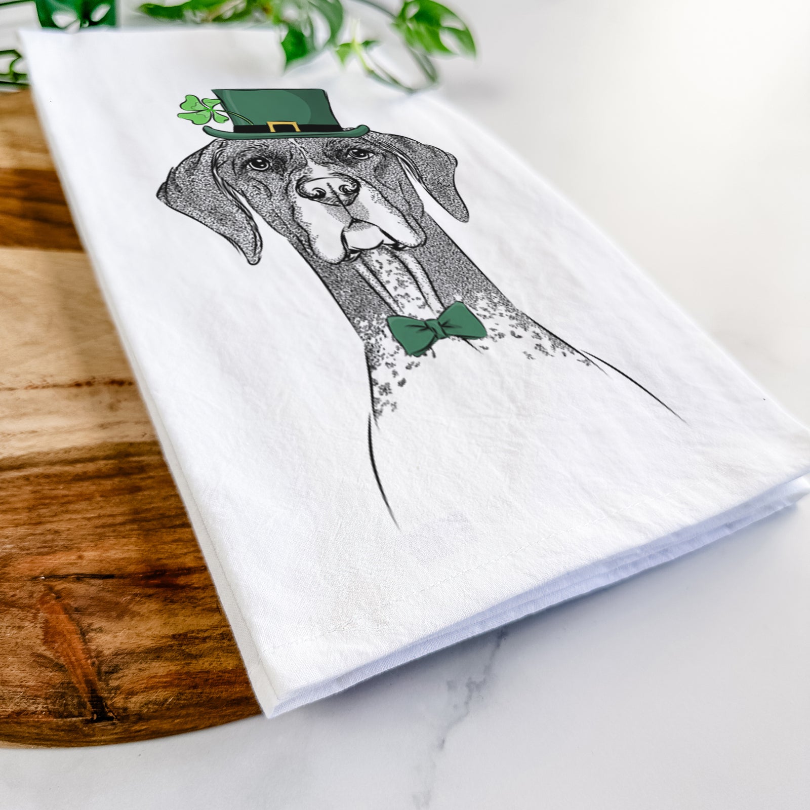 Hand-drawn sketch of Mattis the German Shorthaired Pointer wearing a St. Patrick's Day leprechaun hat and bow tie on a tea towel