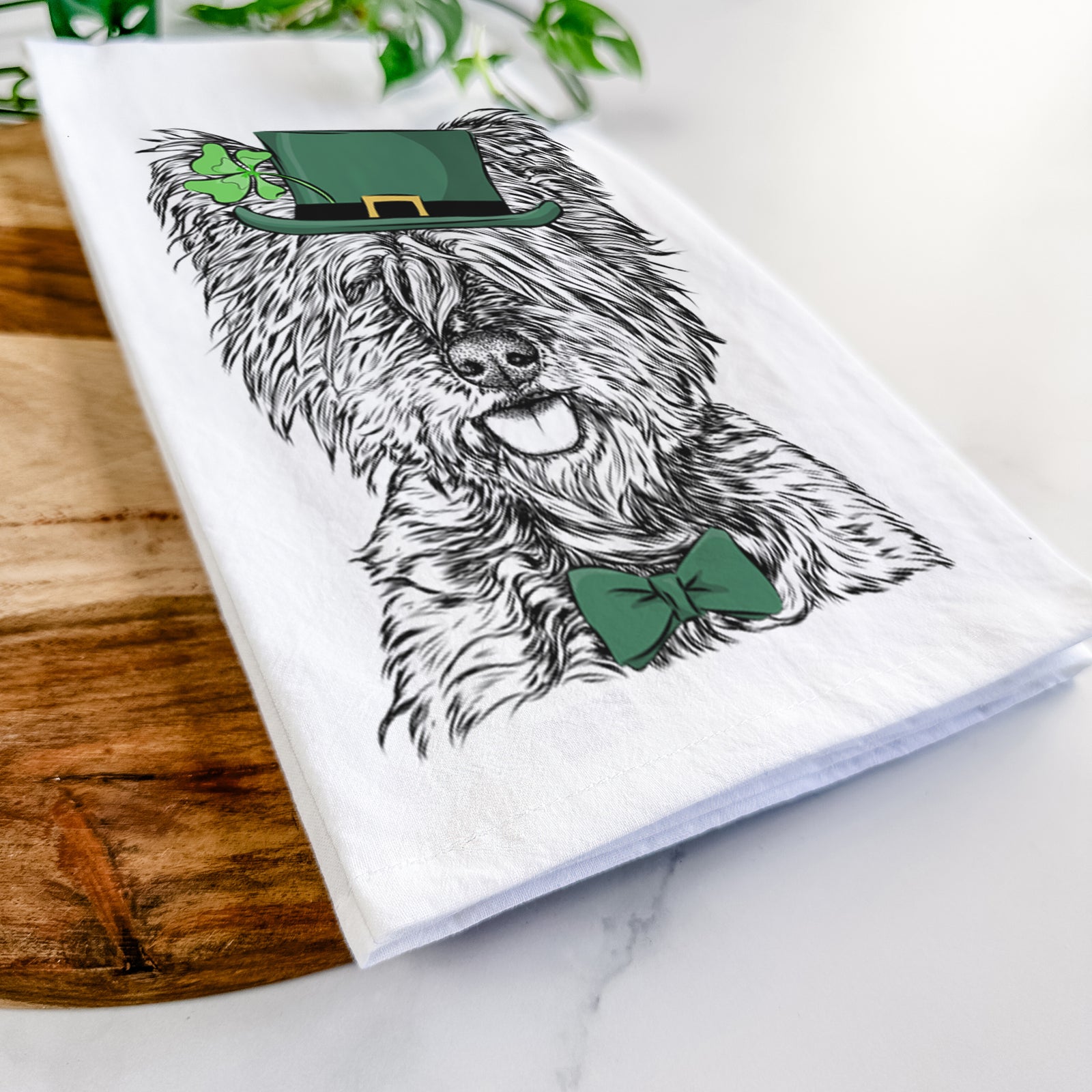 Hand-drawn sketch of McDuff the Cairn Terrier wearing a St. Patrick's Day leprechaun hat and bow tie on a tea towel