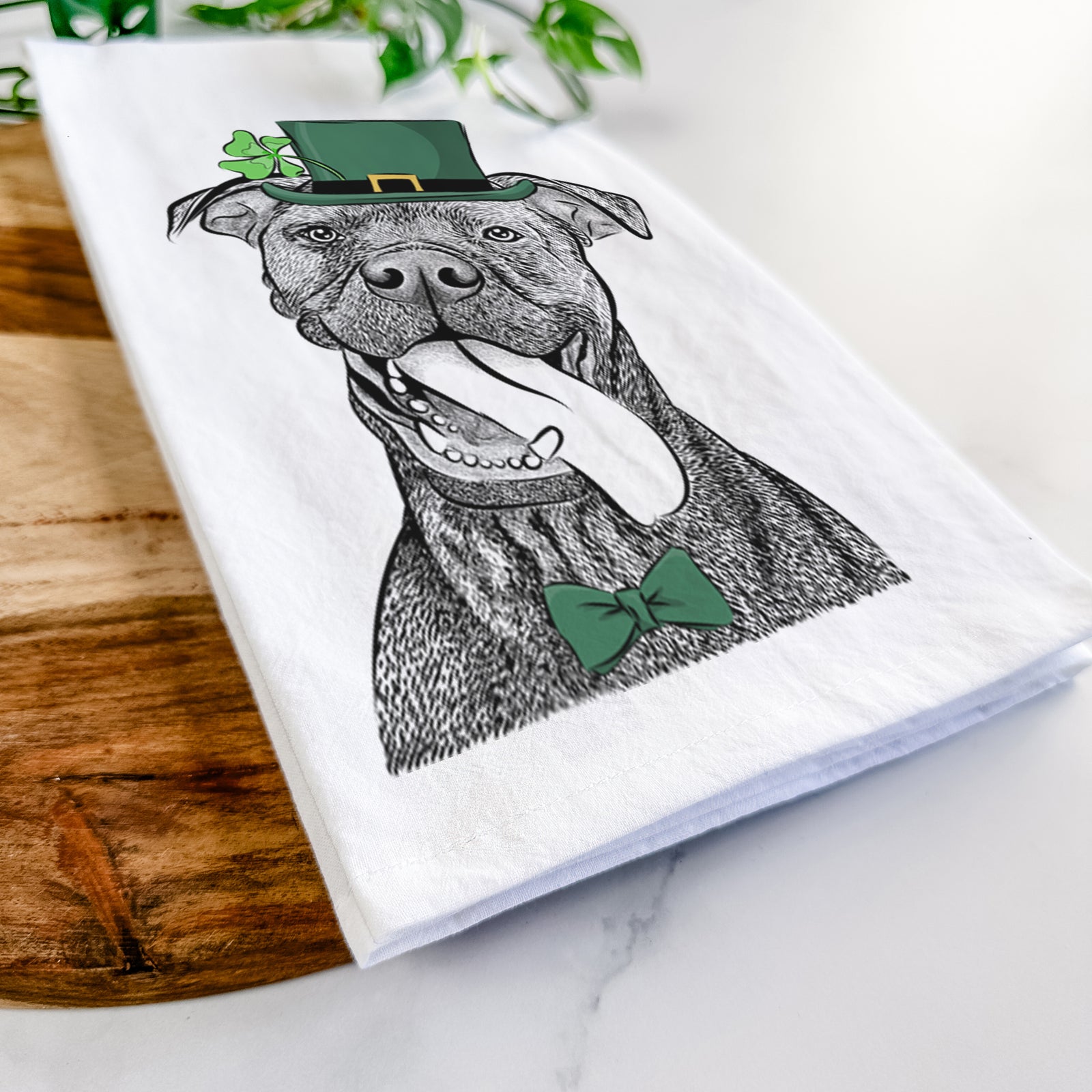 Hand-drawn sketch of Mikey the Boxador wearing a St. Patrick's Day leprechaun hat and bow tie on a tea towel