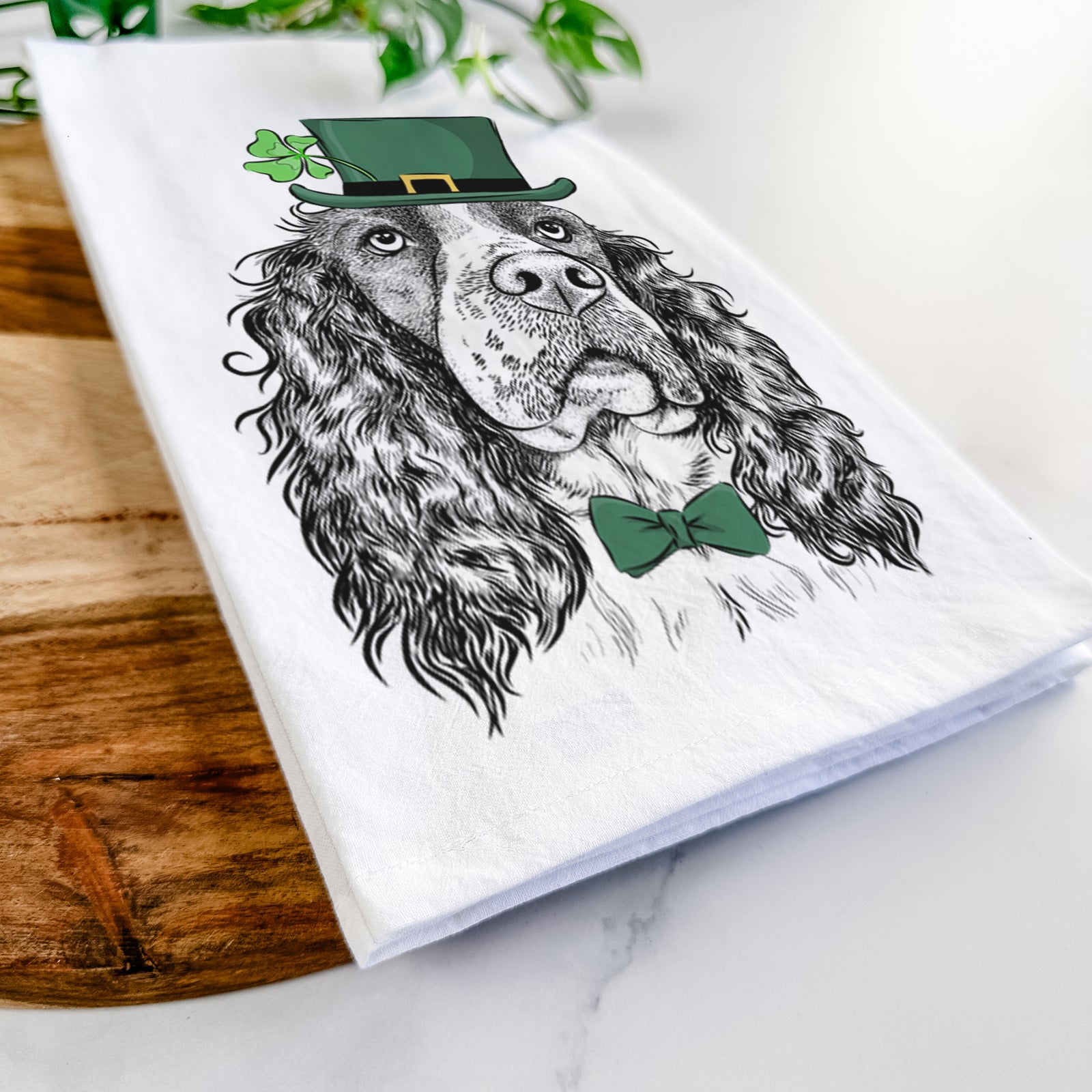 Hand-drawn sketch of Millie Mae the English Springer Spaniel wearing a St. Patrick's Day leprechaun hat and bow tie on a tea towel