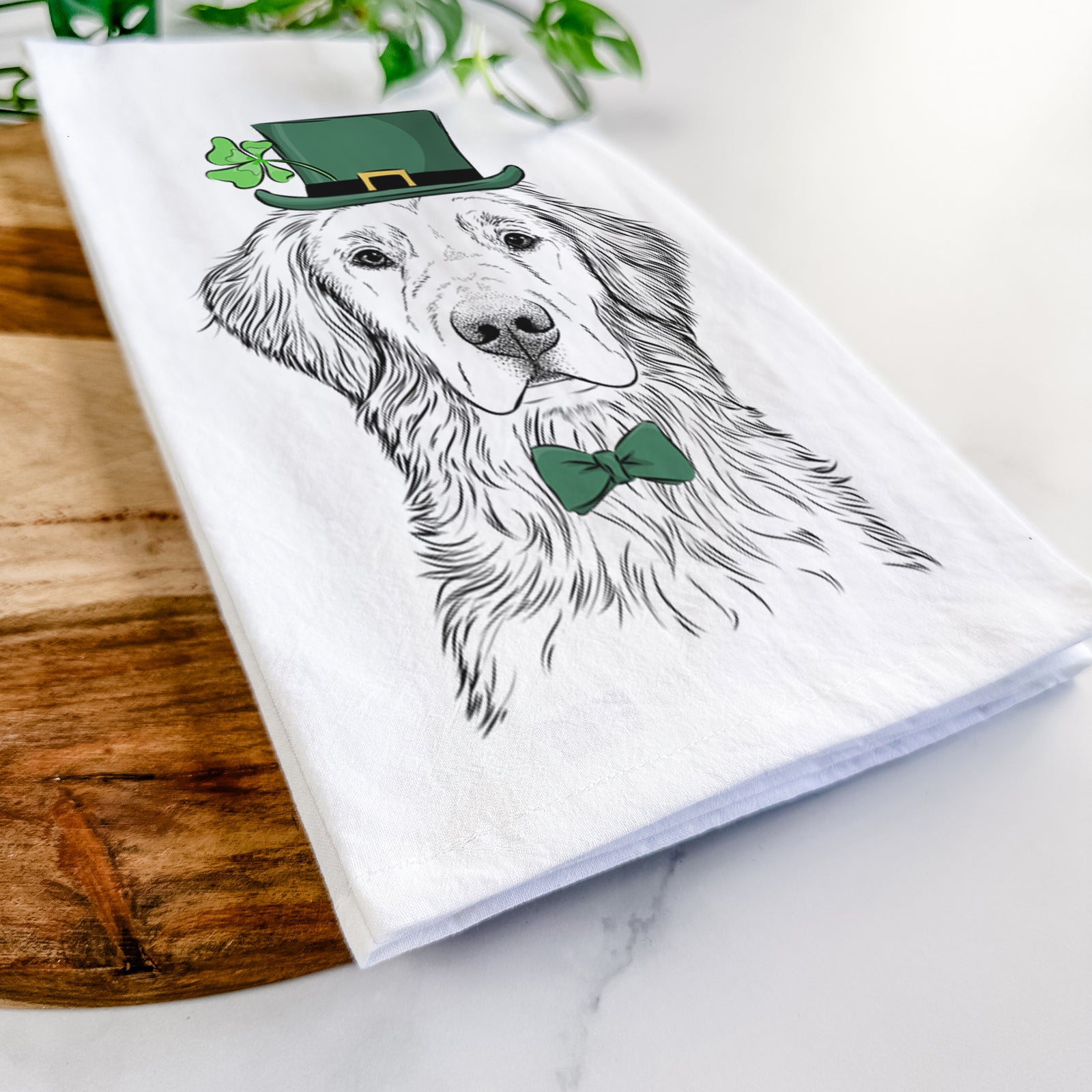 Hand-drawn sketch of Moose the Field Golden Retriever wearing a St. Patrick's Day leprechaun hat and bow tie on a tea towel