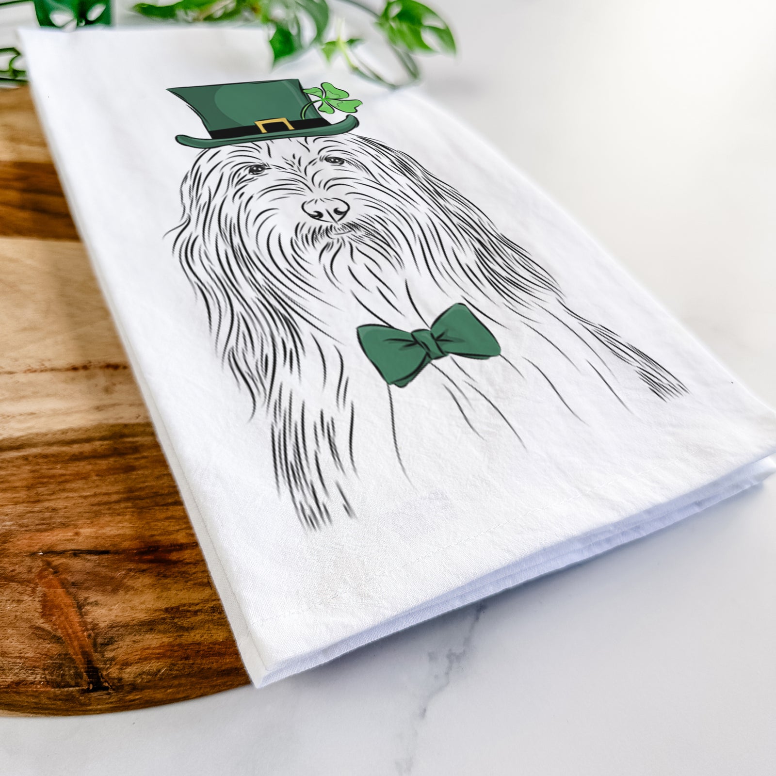 Hand-drawn sketch of Murray the Bearded Collie wearing a St. Patrick's Day leprechaun hat and bow tie on a tea towel