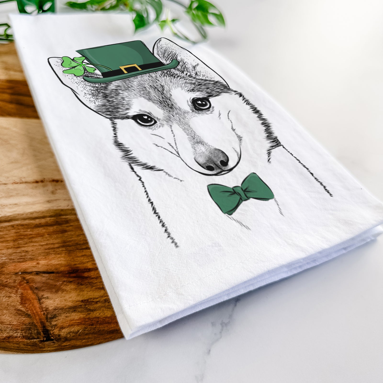 Hand-drawn sketch of Nami the Alaskan Klee Kai wearing a St. Patrick's Day leprechaun hat and bow tie on a tea towel