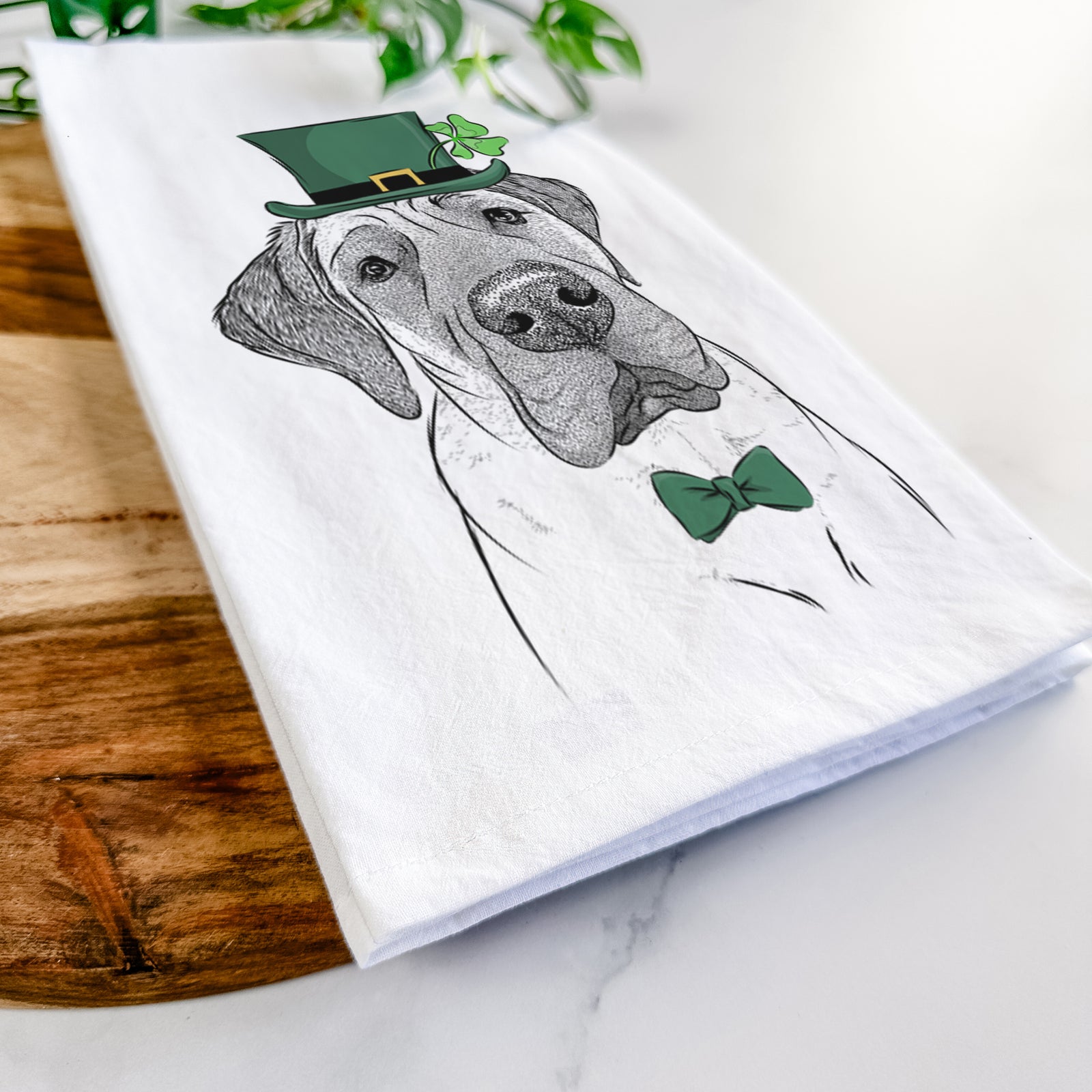 Hand-drawn sketch of Nutterbutter the English Mastiff wearing a St. Patrick's Day leprechaun hat and bow tie on a tea towel