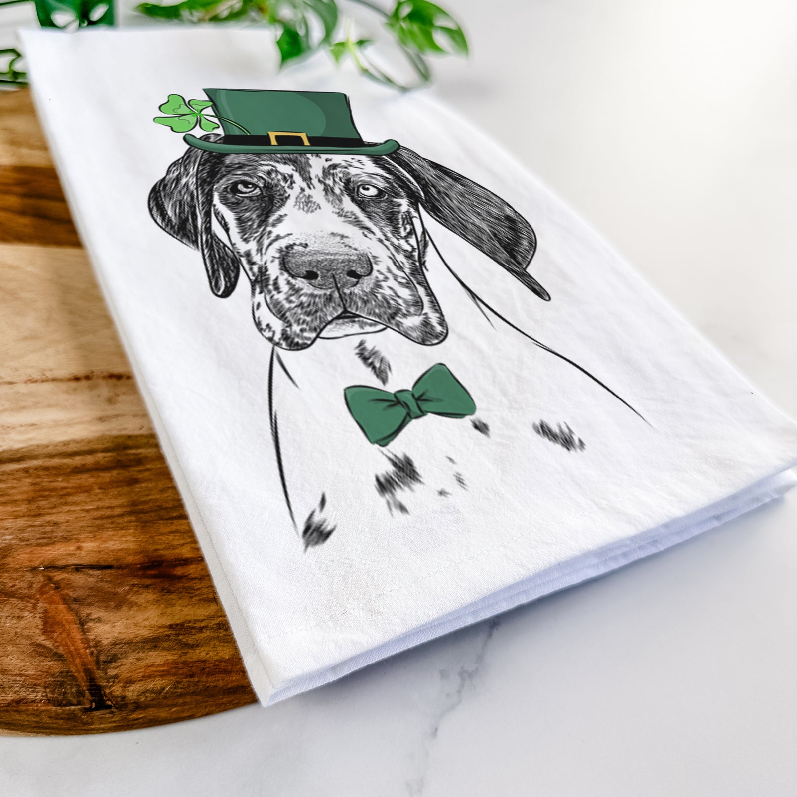 Hand-drawn sketch of Nyx the Great Dane wearing a St. Patrick's Day leprechaun hat and bow tie on a tea towel