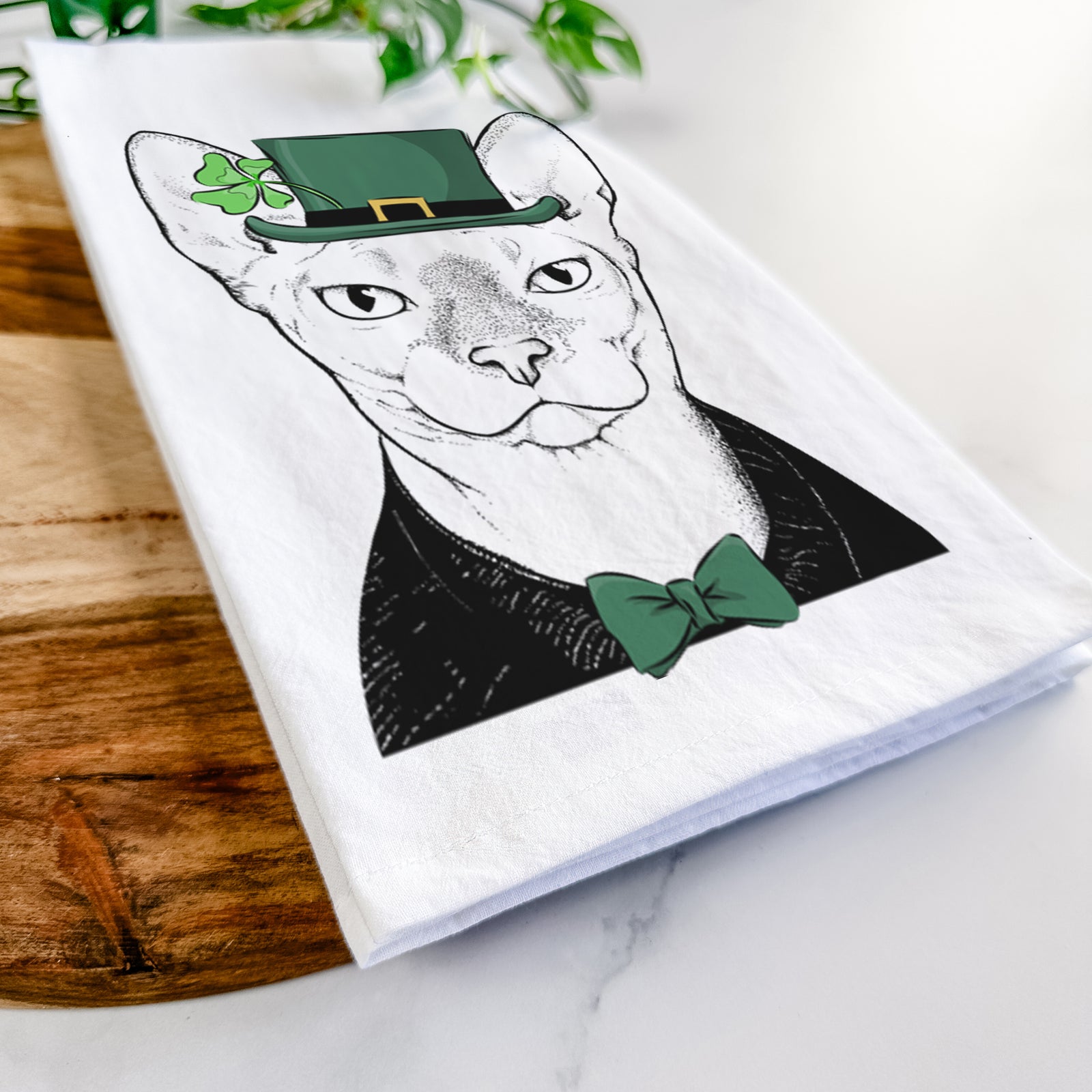 Hand-drawn sketch of Oliver Watson the Sphynx Cat wearing a St. Patrick's Day leprechaun hat and bow tie on a tea towel