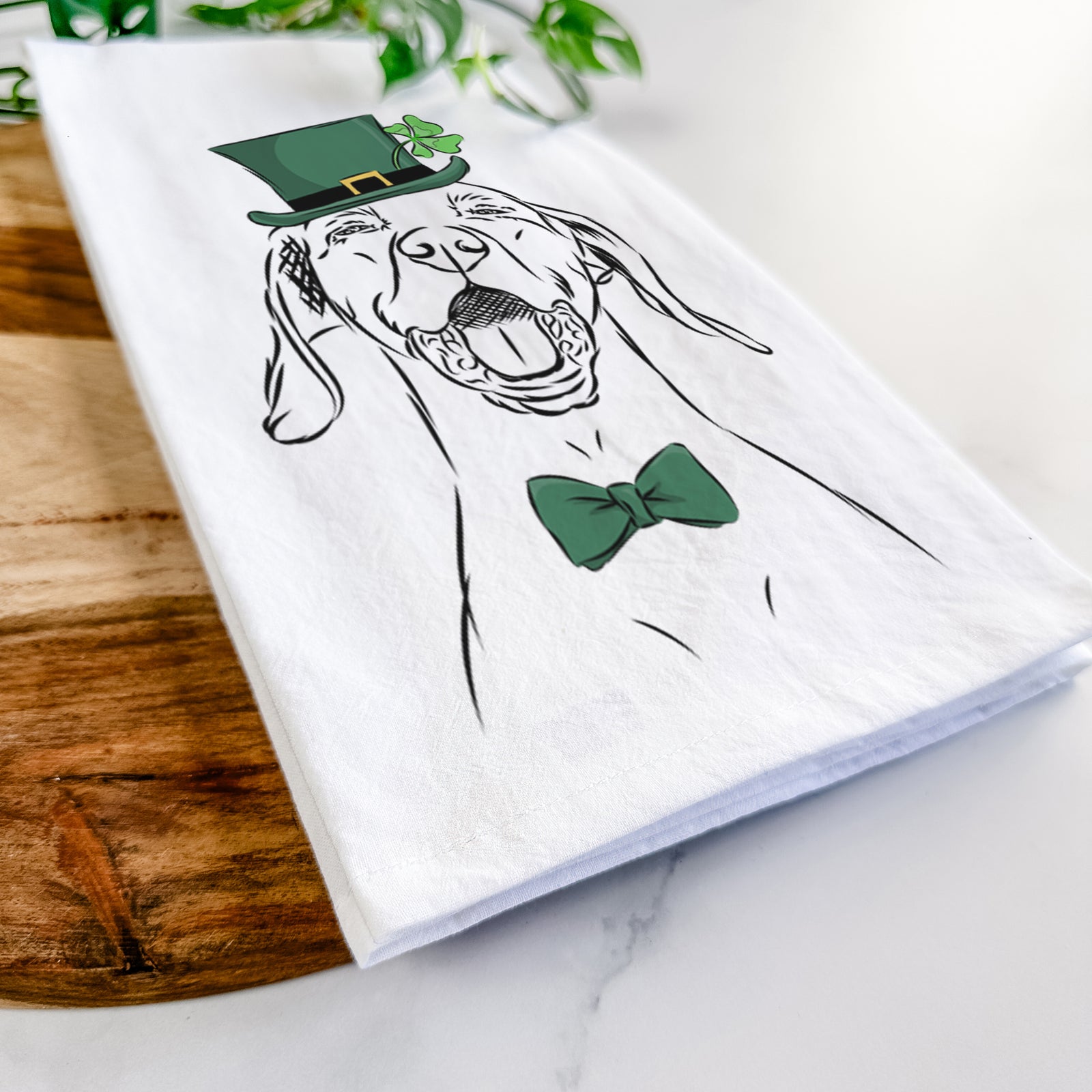 Hand-drawn sketch of Ollie the Vizsla wearing a St. Patrick's Day leprechaun hat and bow tie on a tea towel