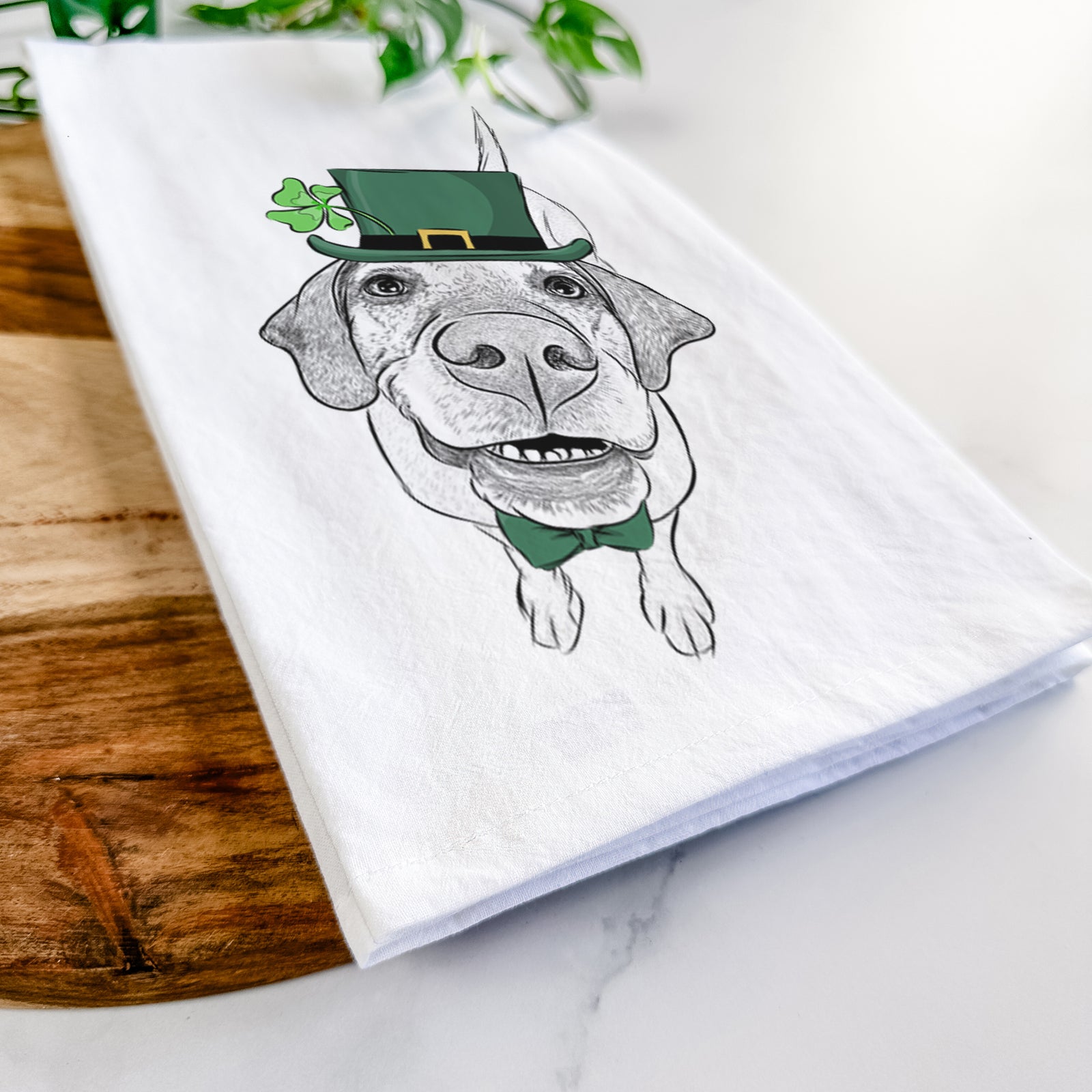 Hand-drawn sketch of Oquirrh the Vizsla wearing a St. Patrick's Day leprechaun hat and bow tie on a tea towel