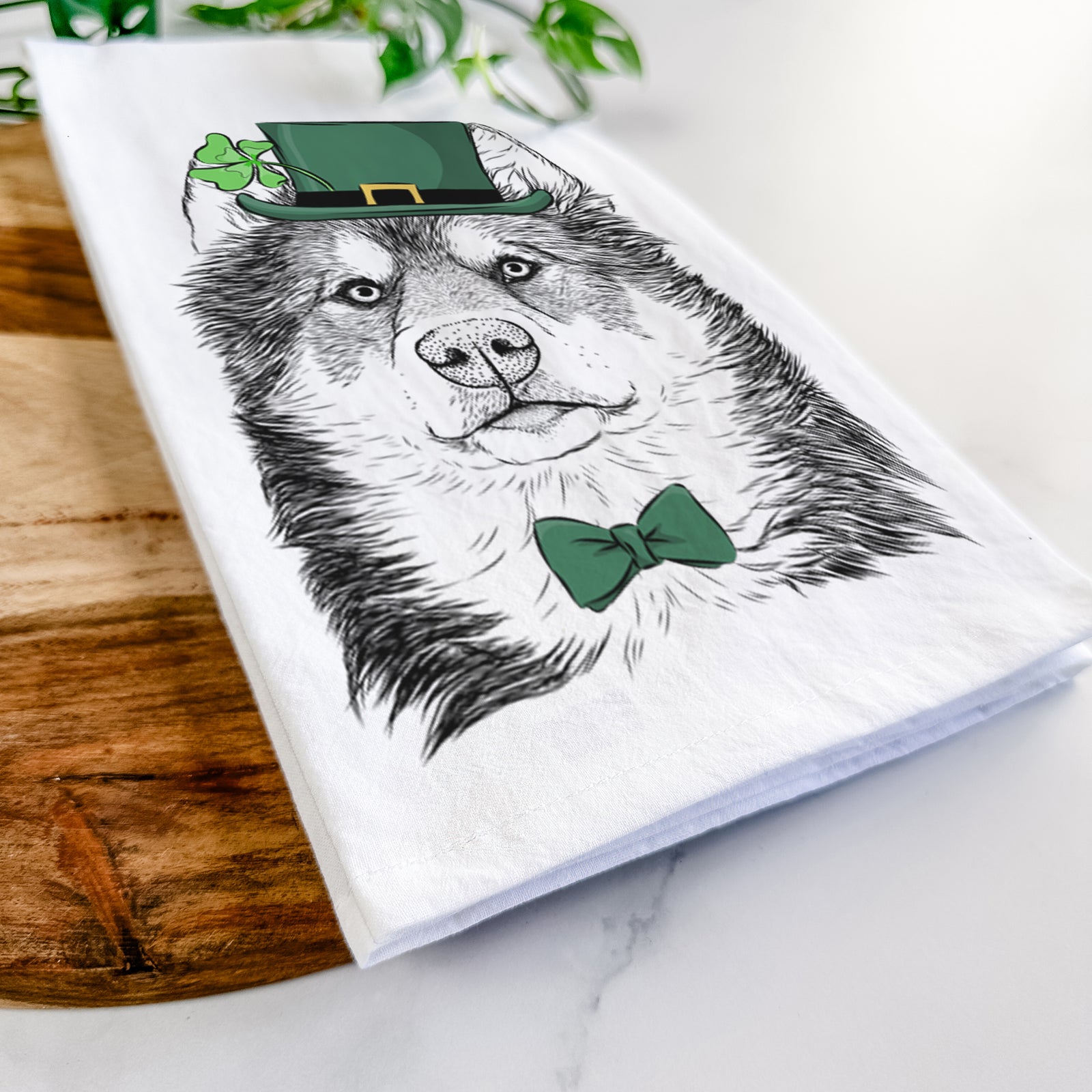 Hand-drawn sketch of Oskar the Canadian Eskimo Dog wearing a St. Patrick's Day leprechaun hat and bow tie on a tea towel