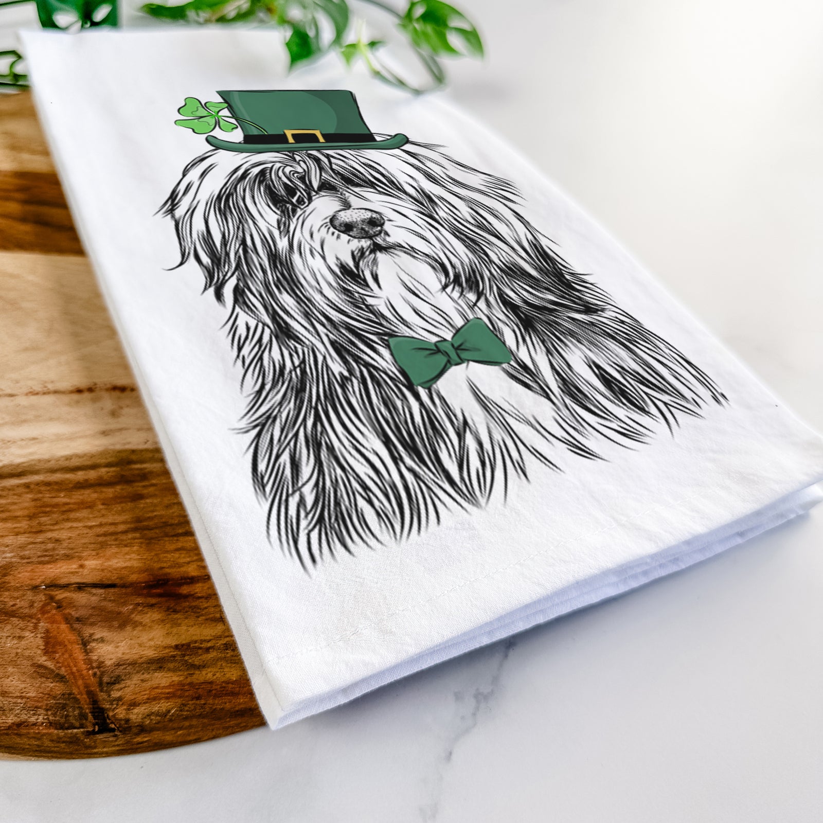 Hand-drawn sketch of Otto the Polish Lowland Sheepdog wearing a St. Patrick's Day leprechaun hat and bow tie on a tea towel