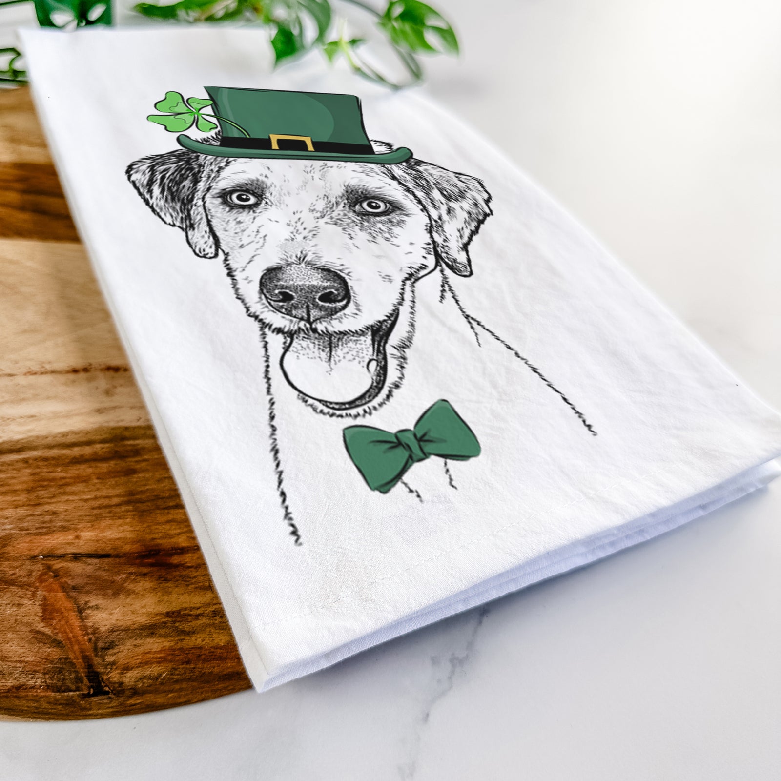 Hand-drawn sketch of Palm Palm the Aussiedoodle wearing a St. Patrick's Day leprechaun hat and bow tie on a tea towel
