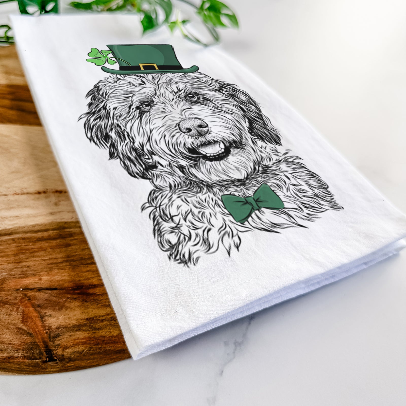 Hand-drawn sketch of Palmer the Aussiedoodle wearing a St. Patrick's Day leprechaun hat and bow tie on a tea towel