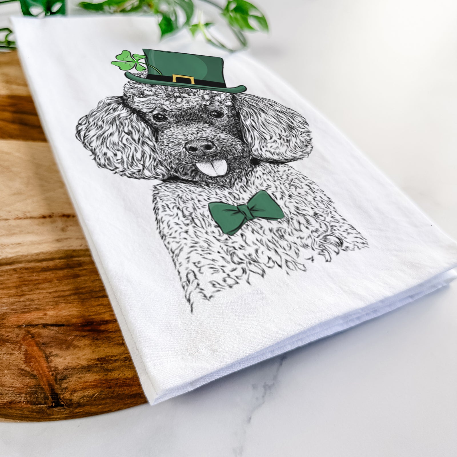 Hand-drawn sketch of George the Toy Poodle wearing a St. Patrick's Day leprechaun hat and bow tie on a tea towel