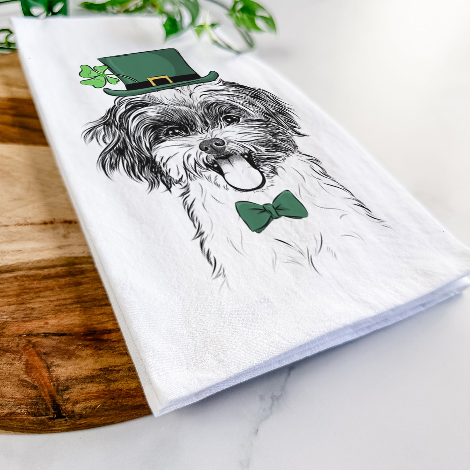 Hand-drawn sketch of Pepper the Shihpoo wearing a St. Patrick's Day leprechaun hat and bow tie on a tea towel