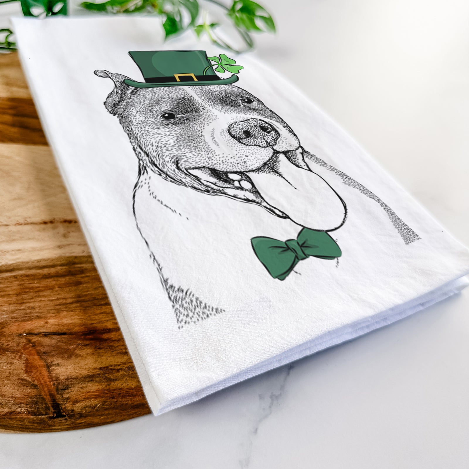Hand-drawn sketch of Piggy the American Staffordshire Terrier wearing a St. Patrick's Day leprechaun hat and bow tie on a tea towel