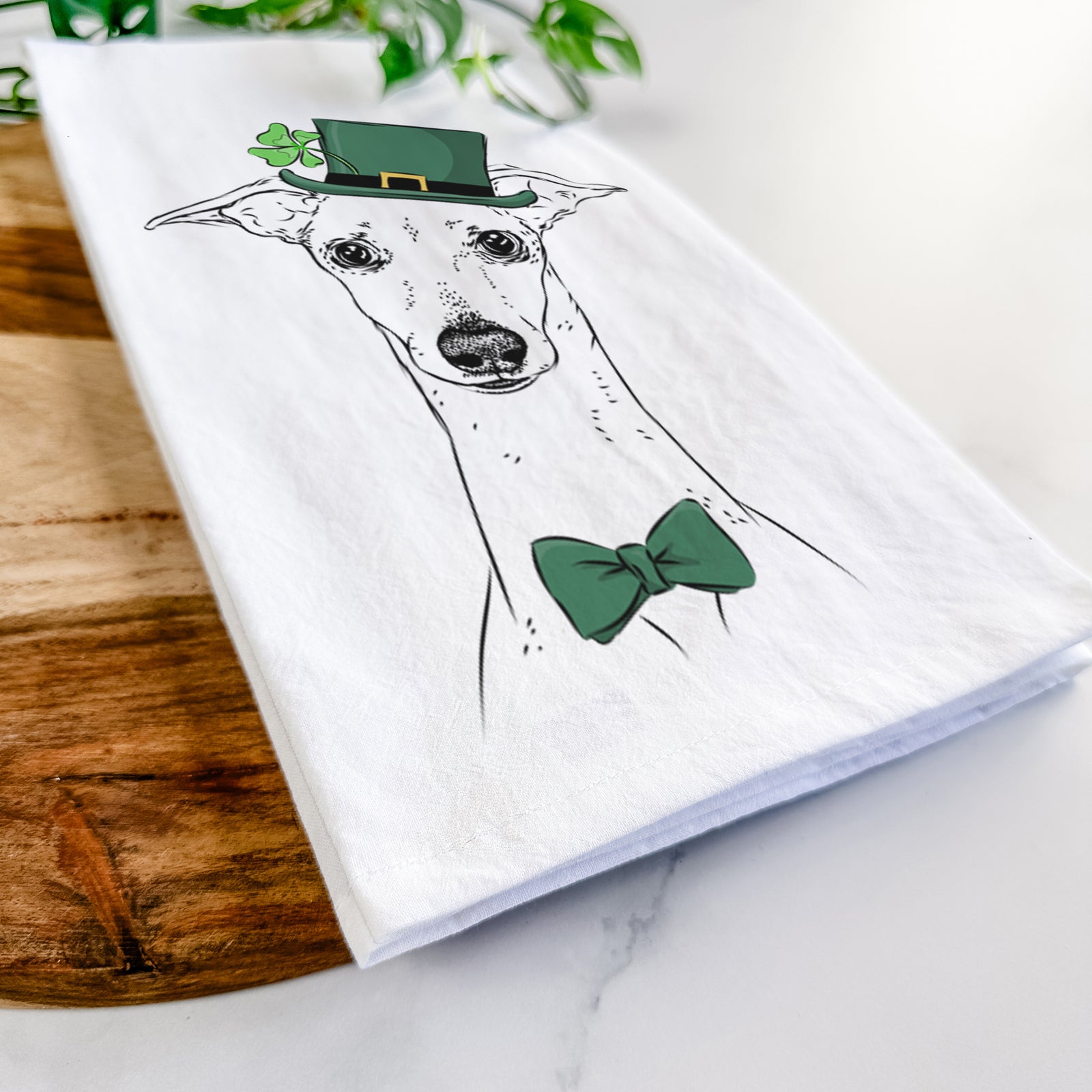 Hand-drawn sketch of Pip the Italian Greyhound wearing a St. Patrick's Day leprechaun hat and bow tie on a tea towel