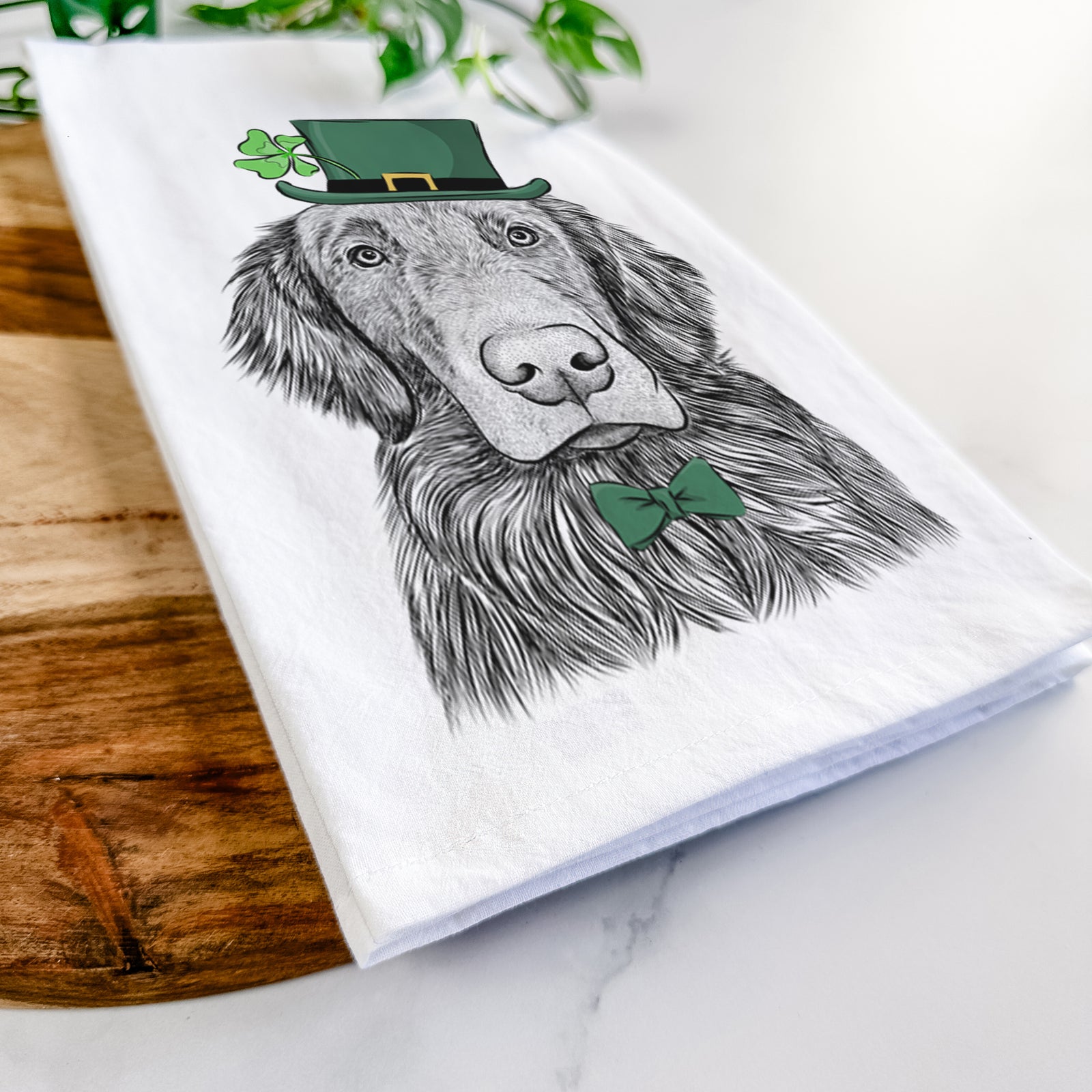 Hand-drawn sketch of Pippin the Flat Coated Retriever wearing a St. Patrick's Day leprechaun hat and bow tie on a tea towel