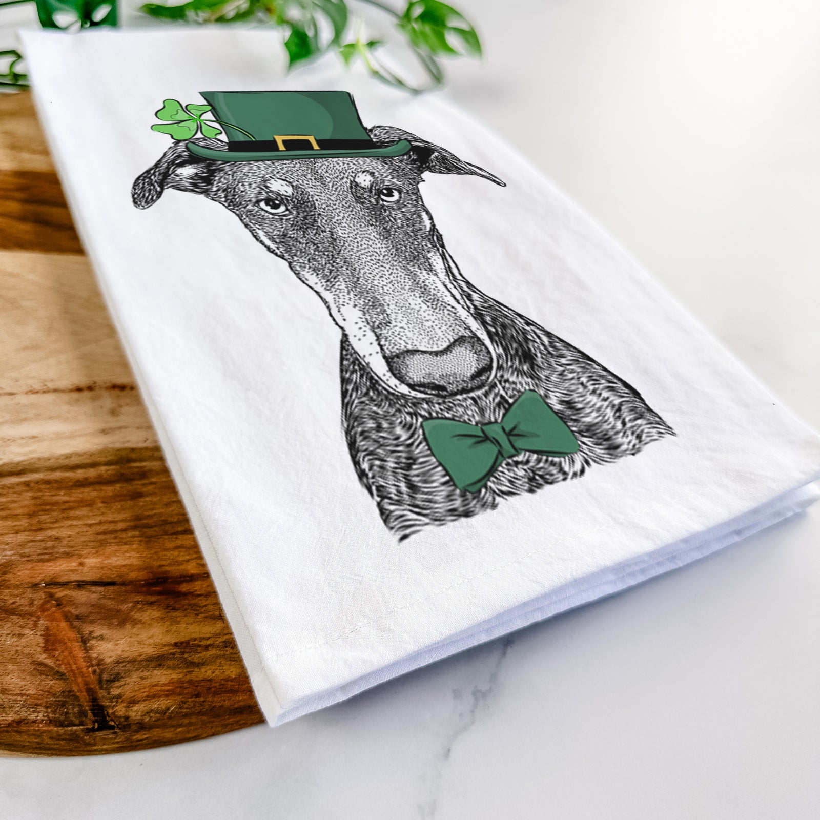 Hand-drawn sketch of Princess Fiona the Doberman Pinscher wearing a St. Patrick's Day leprechaun hat and bow tie on a tea towel
