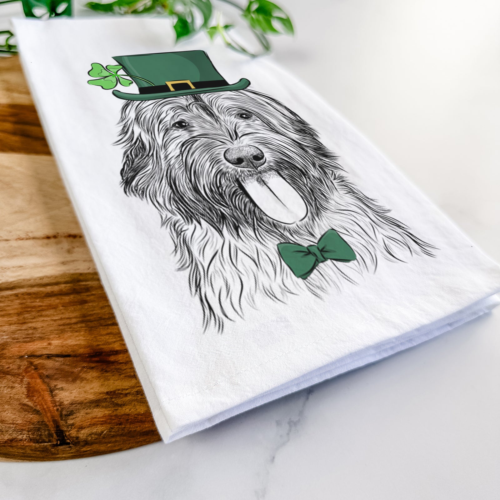 Hand-drawn sketch of Puig the Catalan Sheepdog wearing a St. Patrick's Day leprechaun hat and bow tie on a tea towel