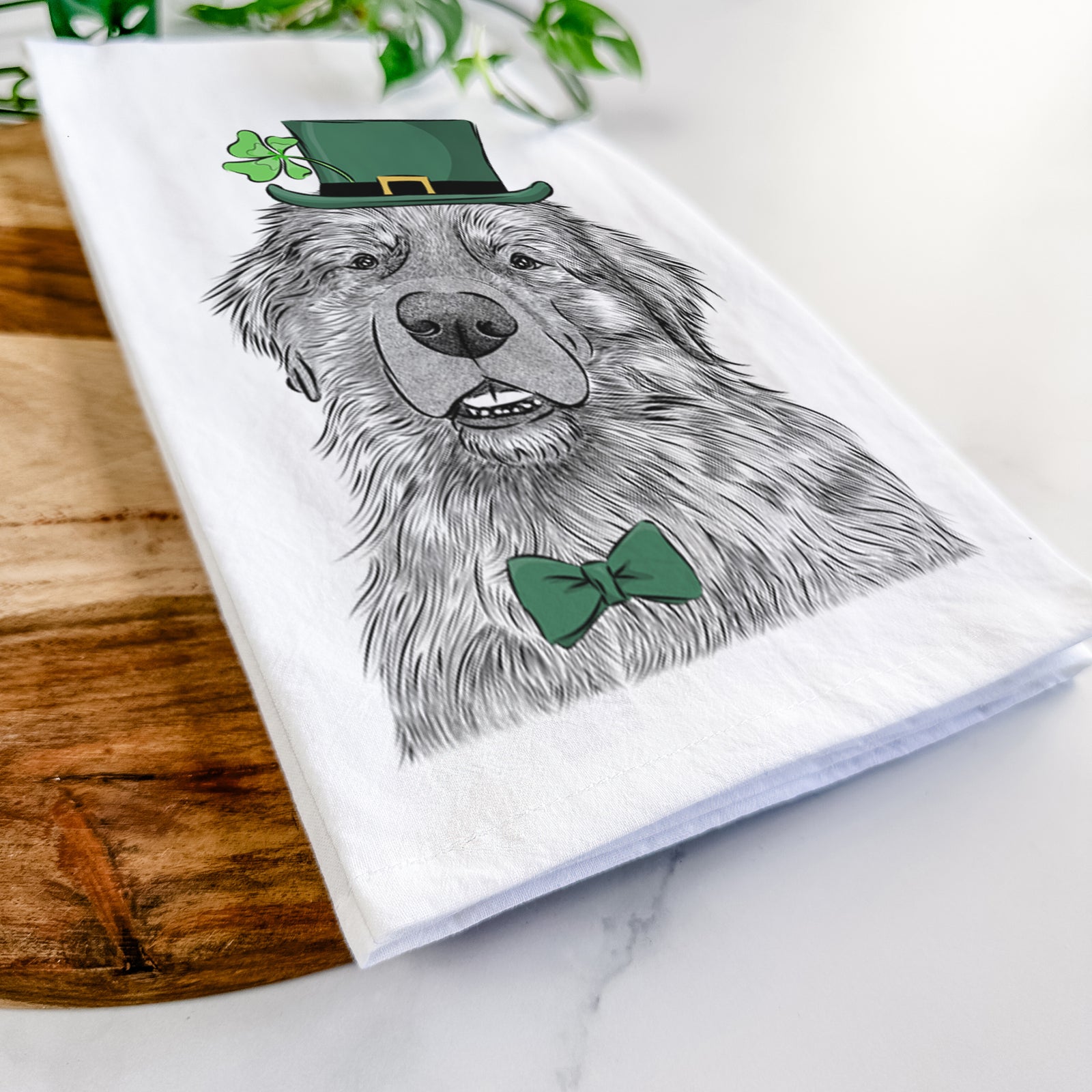 Hand-drawn sketch of Ralph the Leonberger wearing a St. Patrick's Day leprechaun hat and bow tie on a tea towel