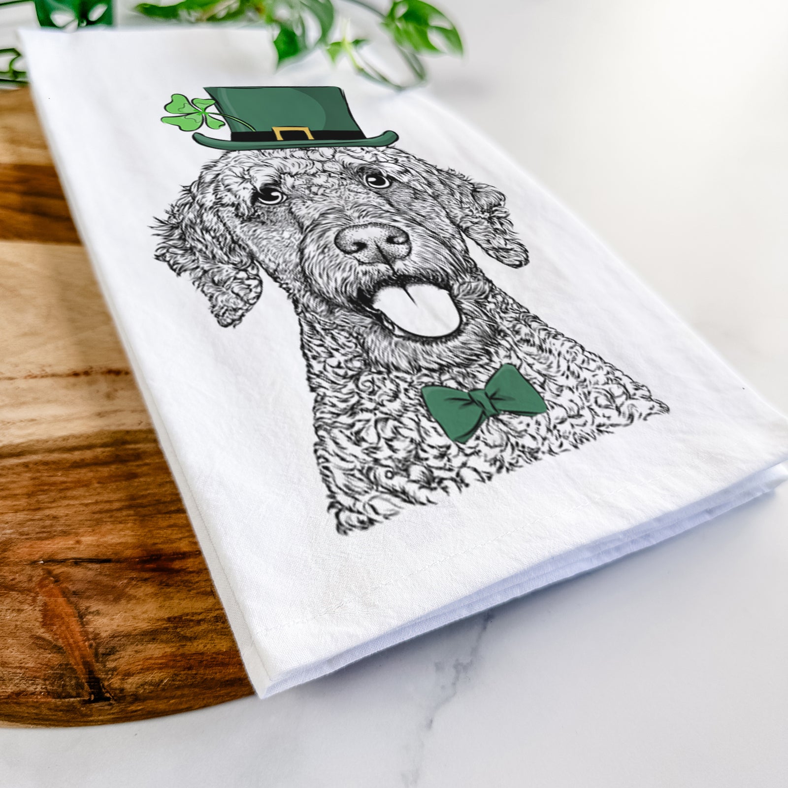 Hand-drawn sketch of Reina the Spanish Water Dog wearing a St. Patrick's Day leprechaun hat and bow tie on a tea towel