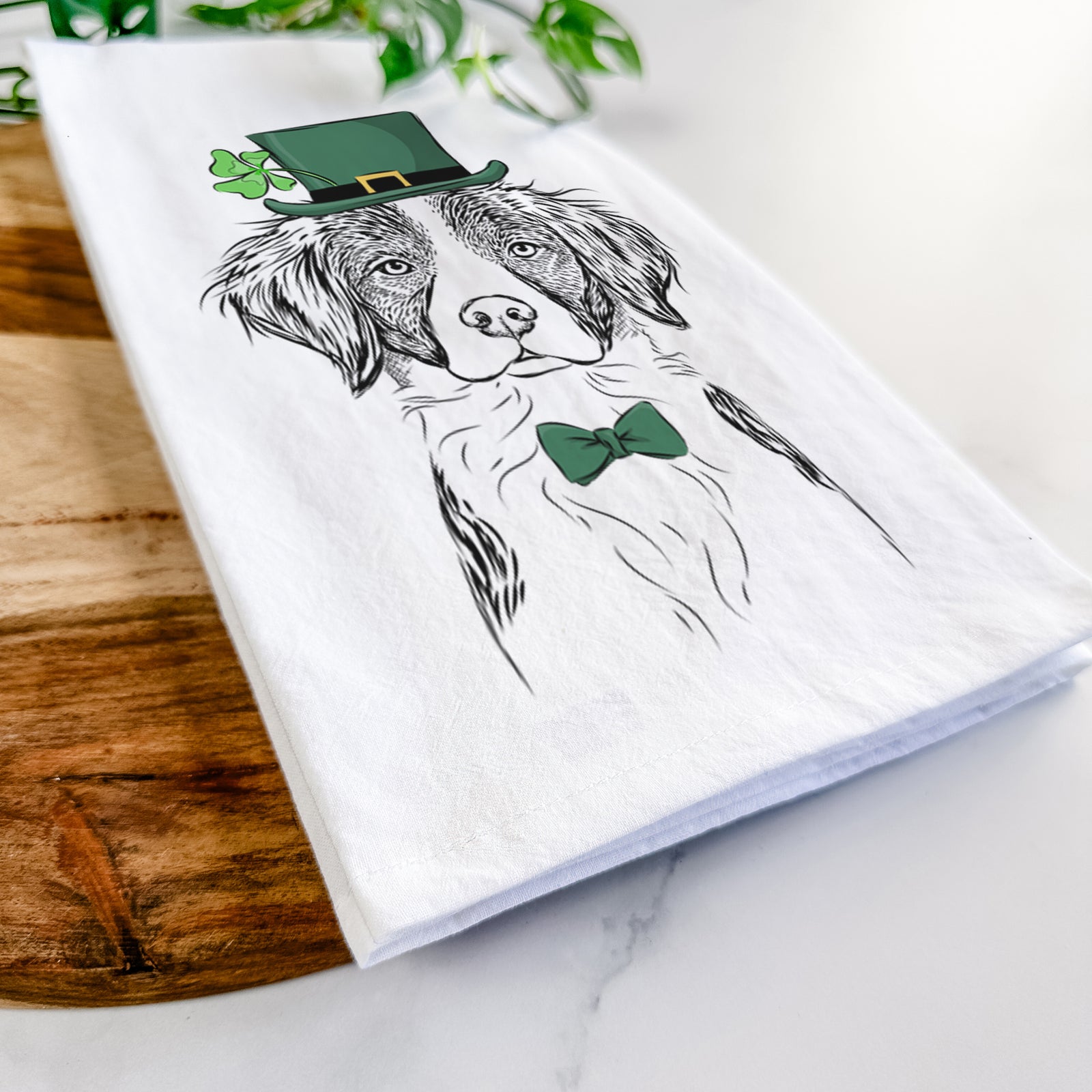 Hand-drawn sketch of Remi the Brittany wearing a St. Patrick's Day leprechaun hat and bow tie on a tea towel
