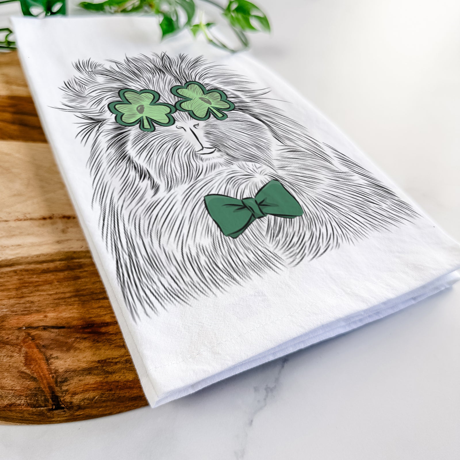 Hand-drawn sketch of Rhino the Guinea Pig wearing a St. Patrick's Day leprechaun hat and bow tie on a tea towel