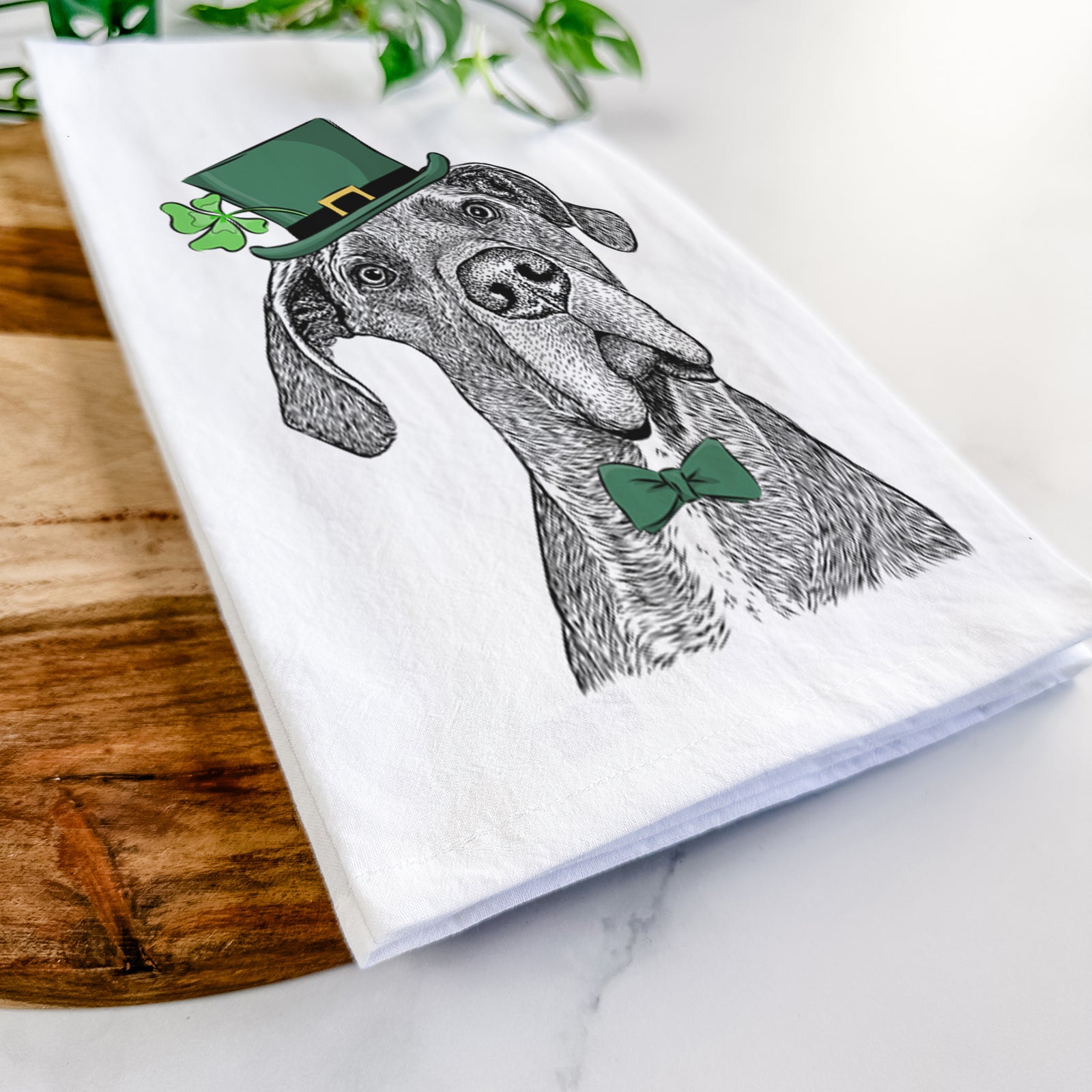 Hand-drawn sketch of River the Great Dane wearing a St. Patrick's Day leprechaun hat and bow tie on a tea towel