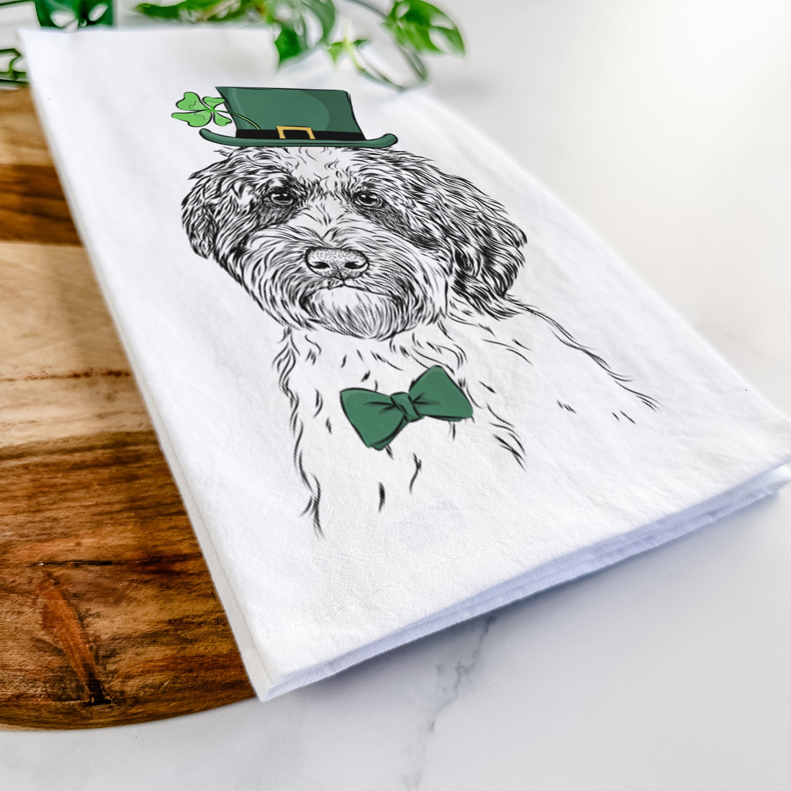Hand-drawn sketch of Rooney the Aussiedoodle wearing a St. Patrick's Day leprechaun hat and bow tie on a tea towel