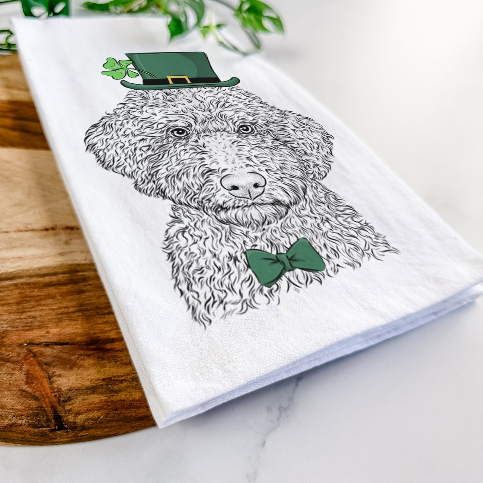 Hand-drawn sketch of Ross the Lagotto Romagnolo wearing a St. Patrick's Day leprechaun hat and bow tie on a tea towel