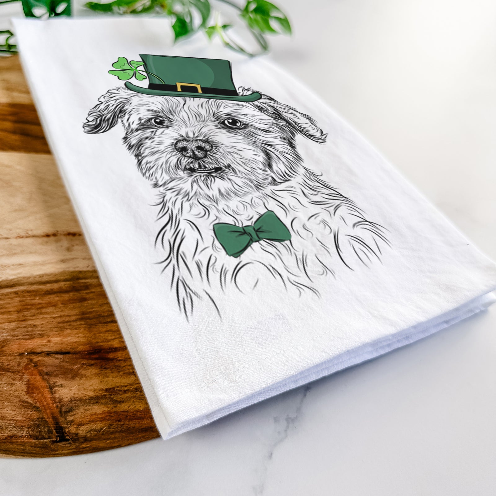 Hand-drawn sketch of Roxie the Schnauzer Shih Tzu Mix wearing a St. Patrick's Day leprechaun hat and bow tie on a tea towel