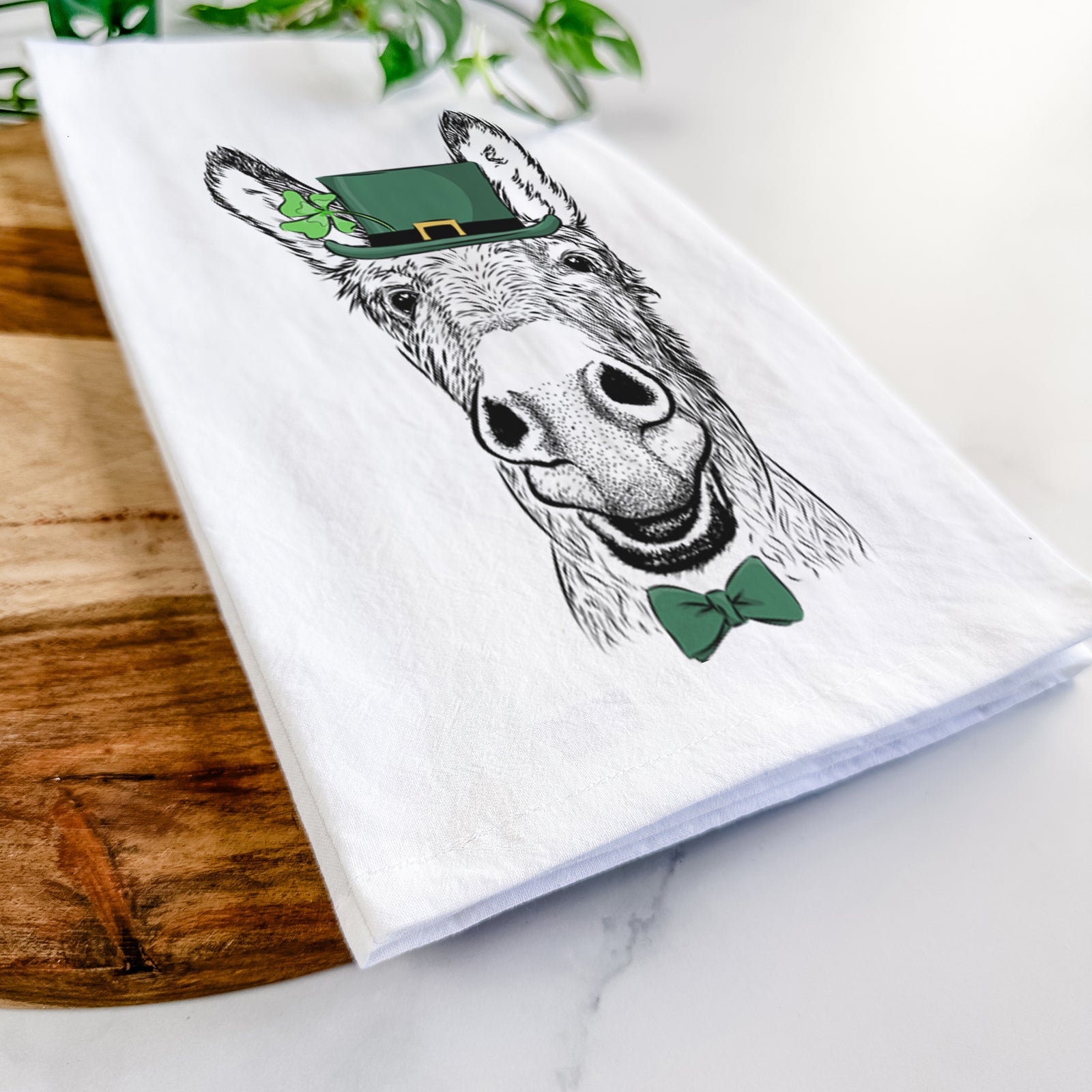 Hand-drawn sketch of Samule the Donkey wearing a St. Patrick's Day leprechaun hat and bow tie on a tea towel